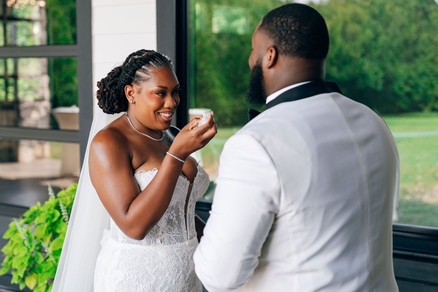 A bride and groom share a joyful moment during their wedding cake cutting ceremony indoors.