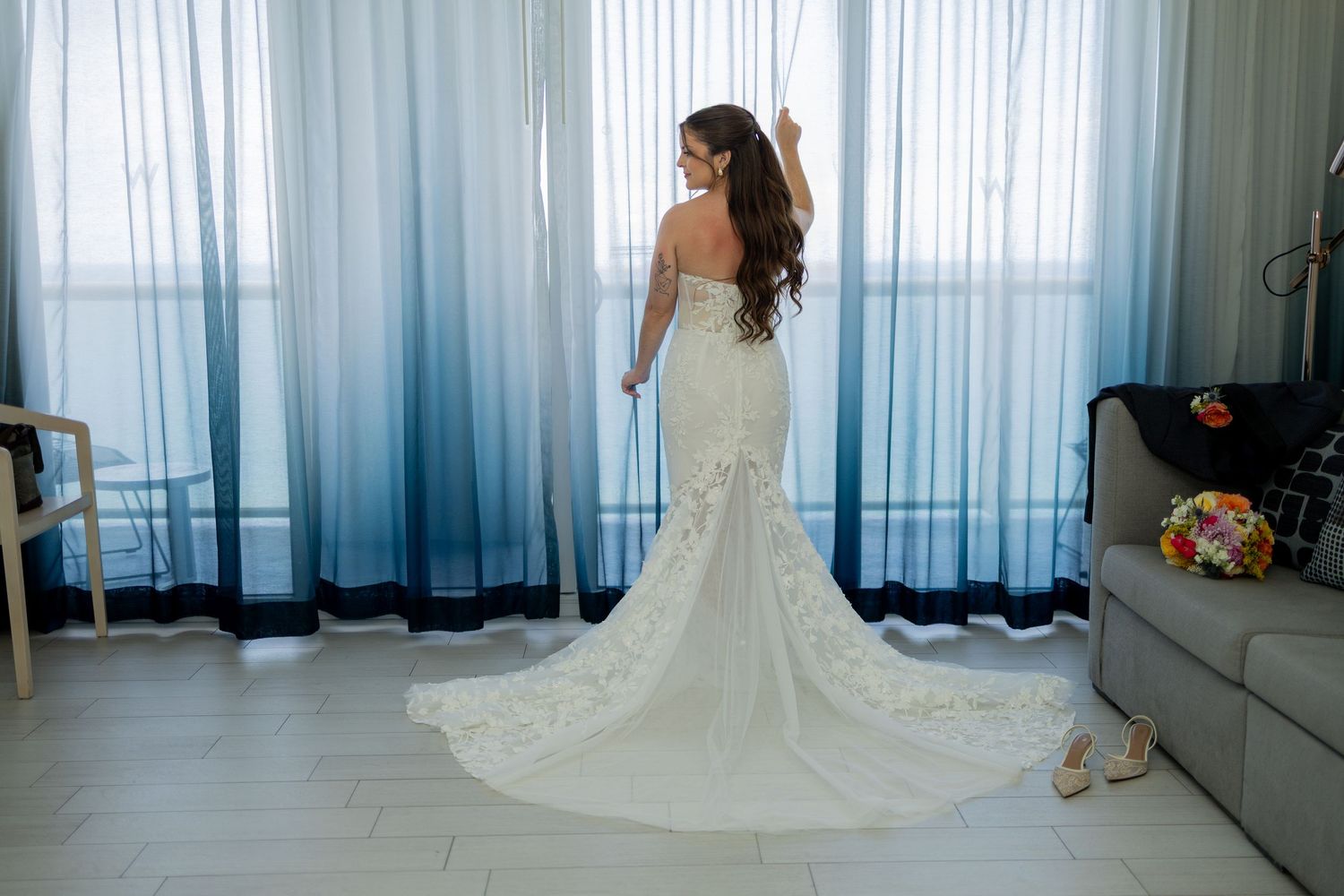 Bride in her wedding dress holding curtain, facing away showing off back or the dress at The W Fort Lauderdale