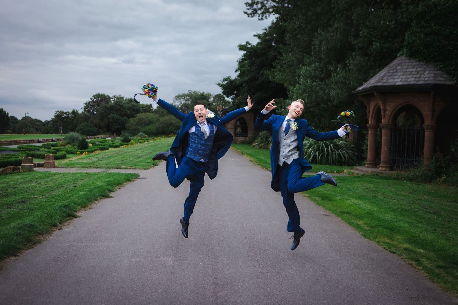 People in blue outfits jumping playfully on a path outdoors.
