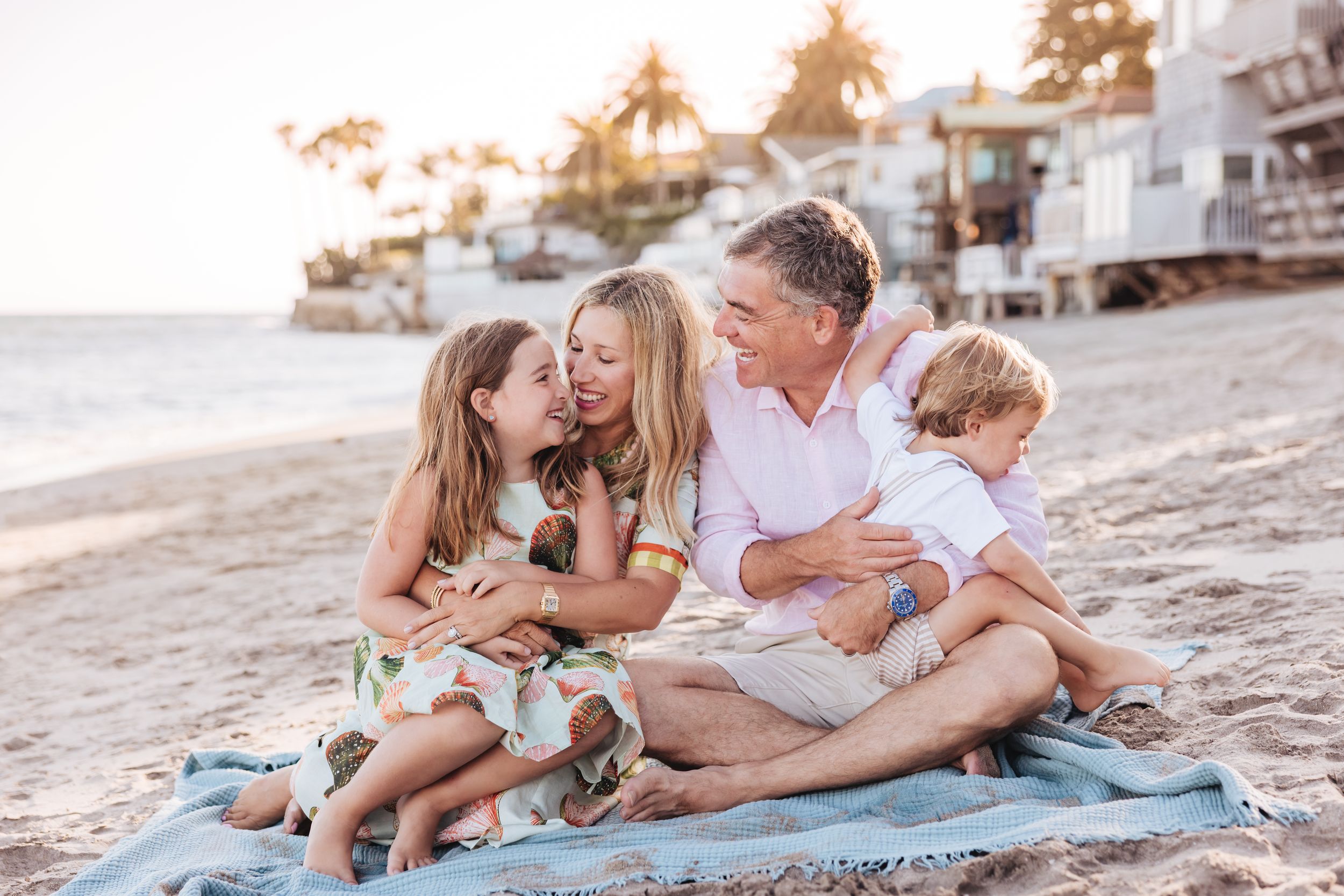 A family sits together laughing and enjoying a cozy moment against a rustic wooden door.