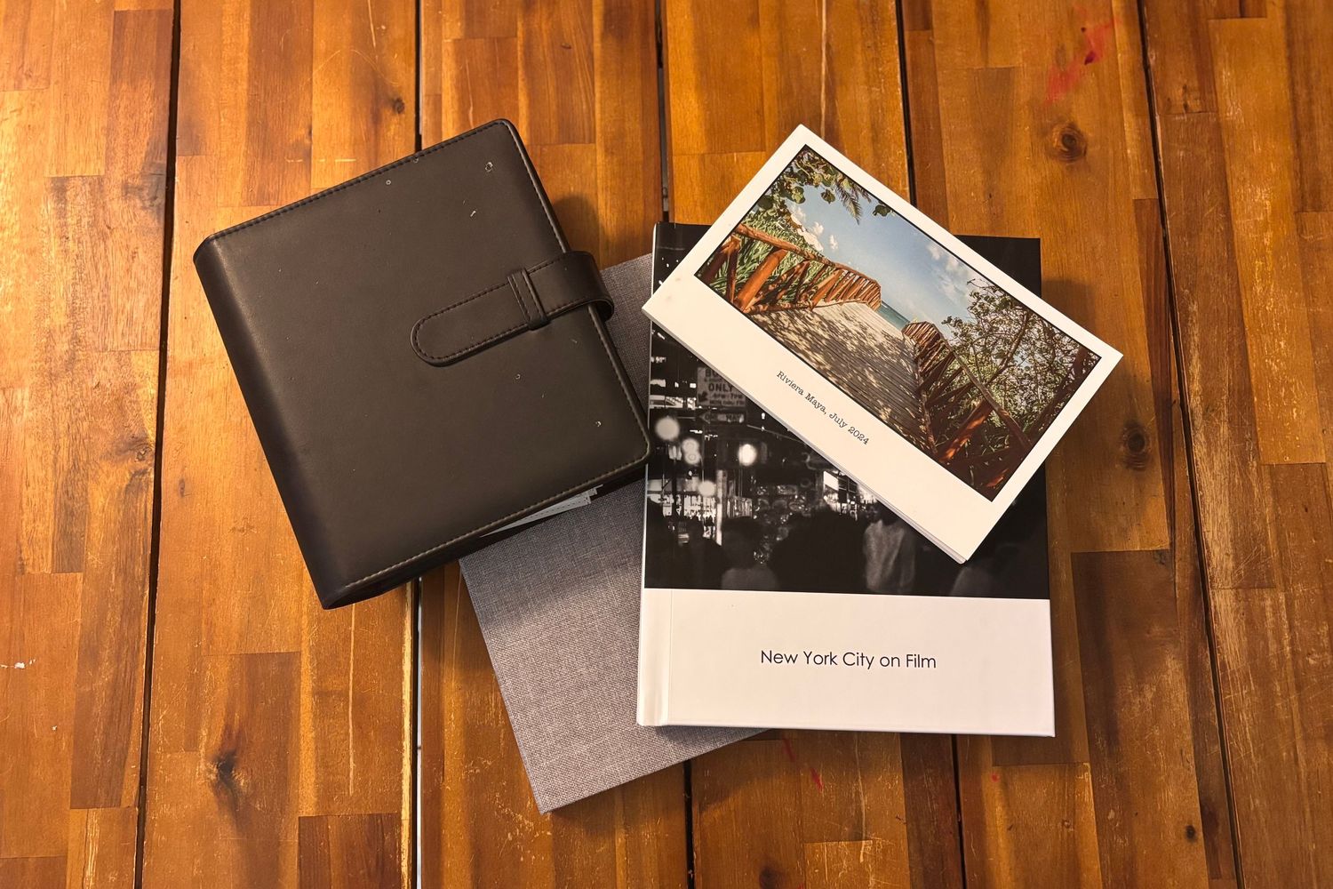 Photo album and printed photographs displayed on wooden floorboards.