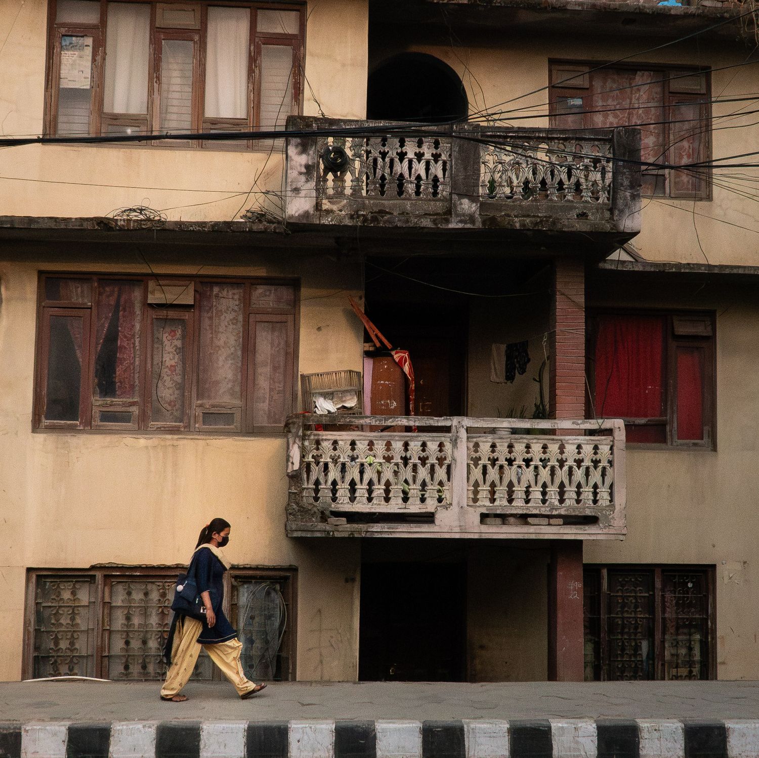 Colonial-style building with ornate balconies in warm tones and a pedestrian walking past.