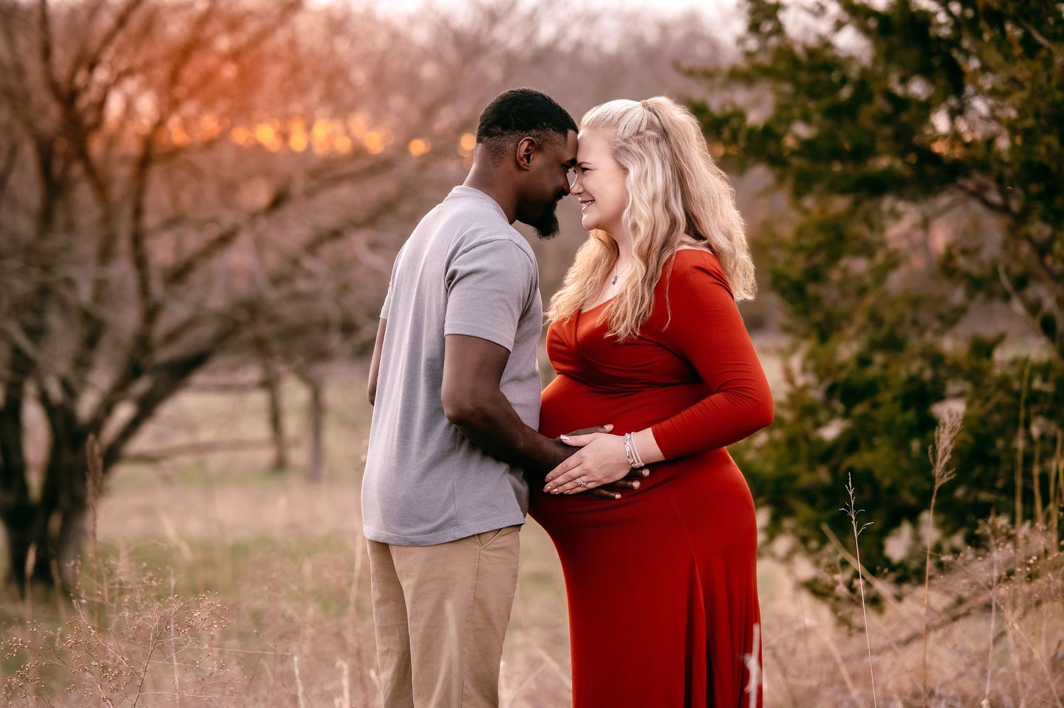 A loving family shares an intimate moment in a golden field at sunset.