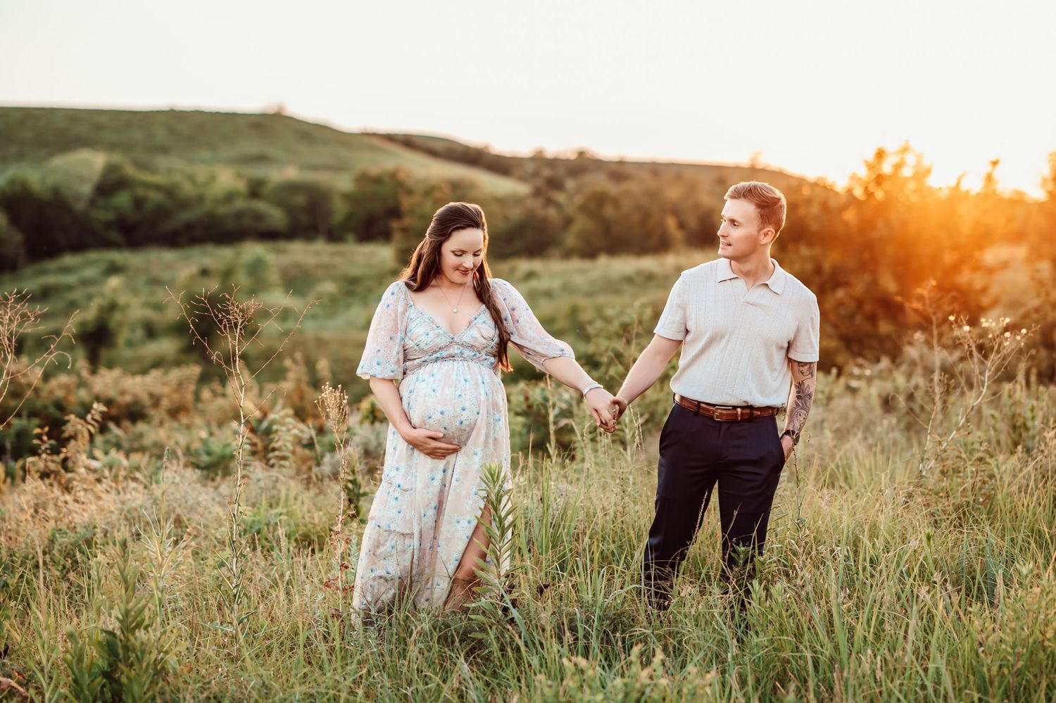 Couple embraces during outdoor maternity photo session with woman wearing vibrant red dress showing her baby bump.