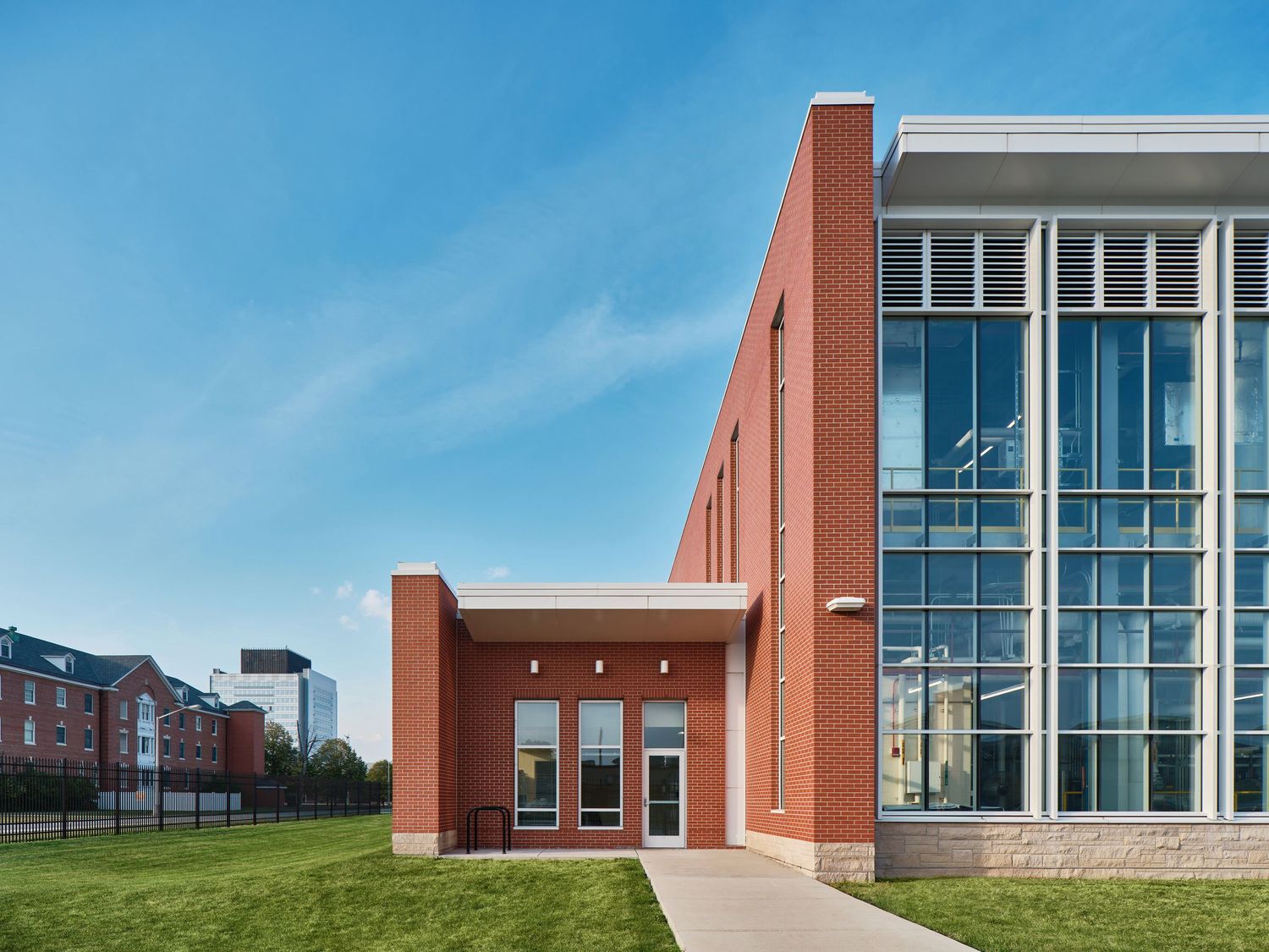 Modern brick medical building with glass windows and entrance walkway under clear blue sky.