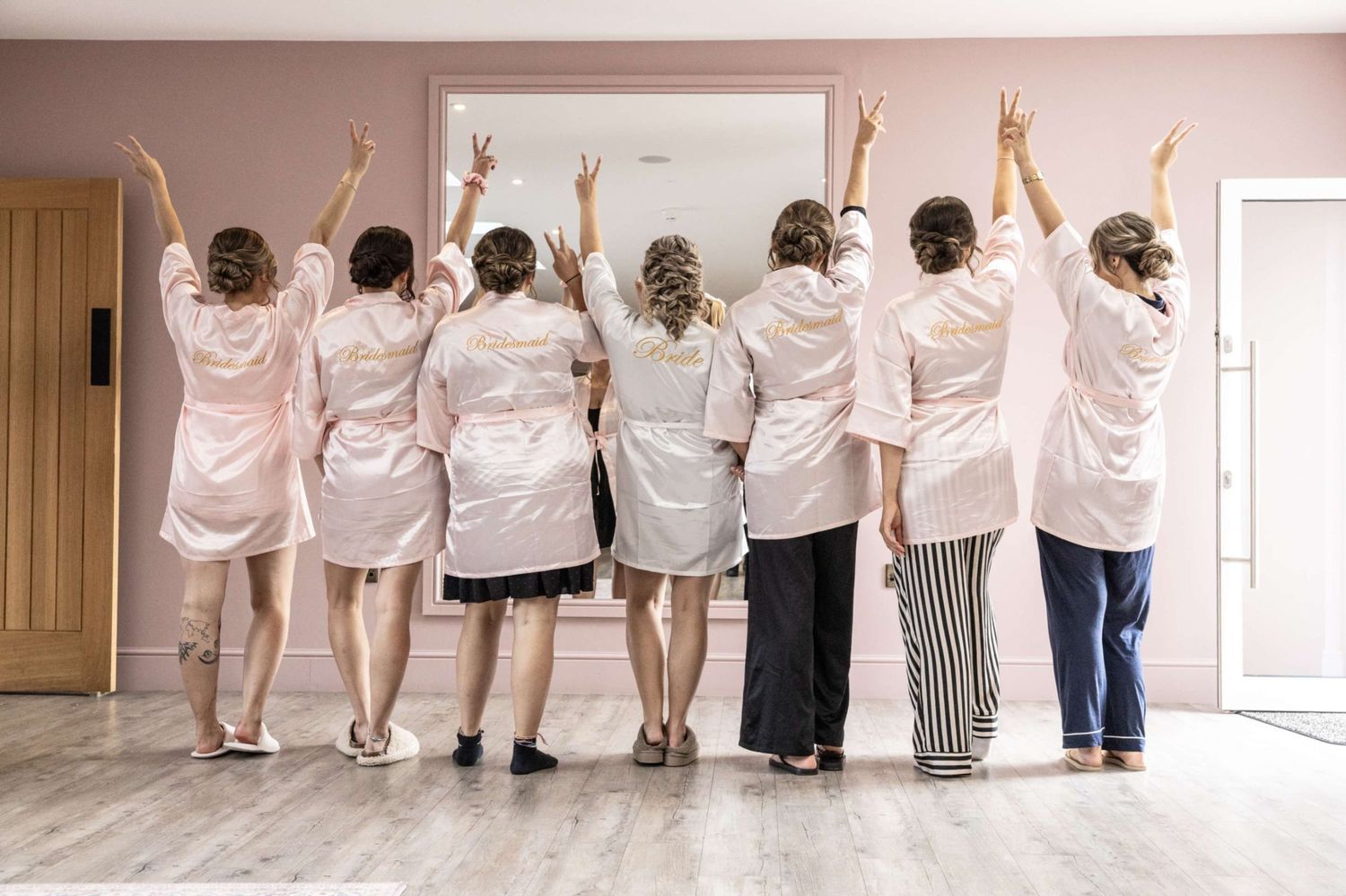 Group wearing matching robes and sleepwear raise their hands while standing with backs turned to camera.
