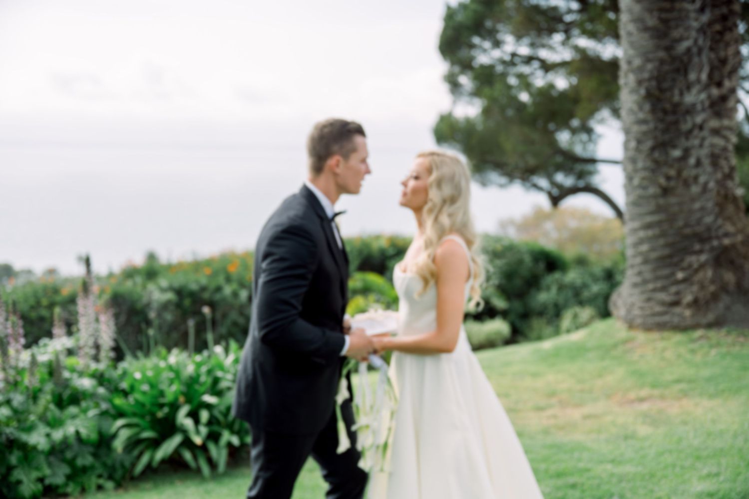 Elegant outdoor wedding ceremony setup with wooden chairs on grass lawn overlooking scenic landscape and pine trees.