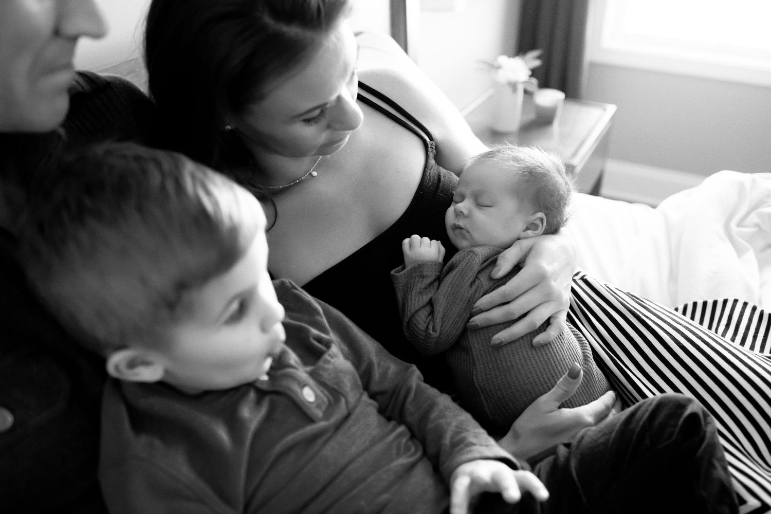 A black and white intimate moment of a family welcoming a newborn baby.