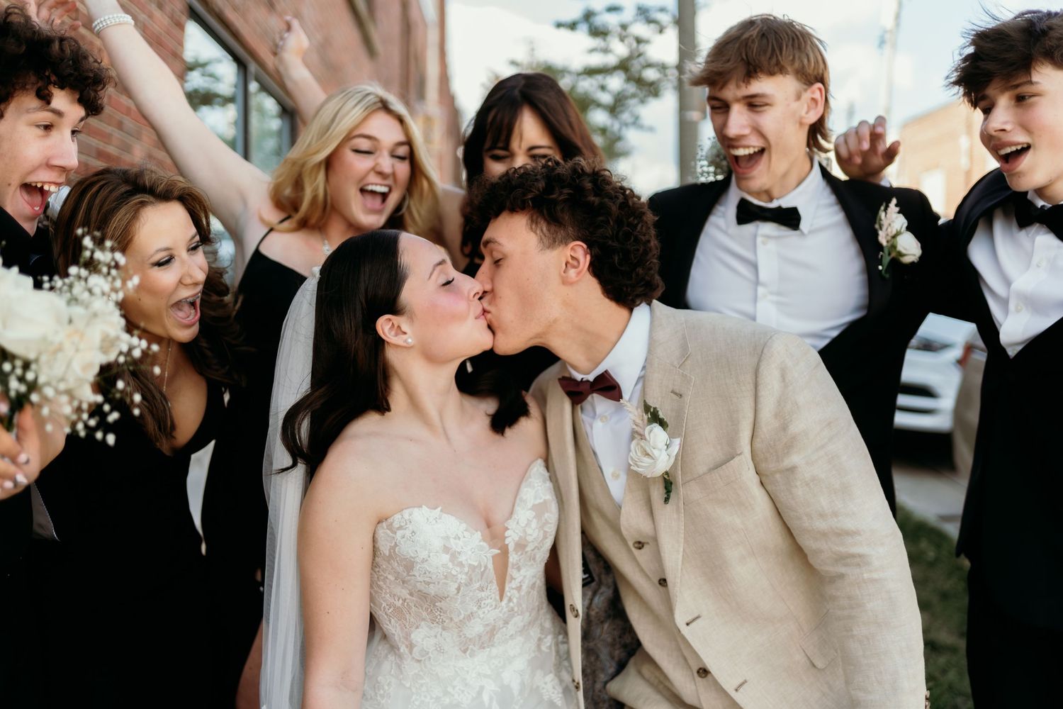 Joyful wedding party celebrating and laughing together outside in formal attire.