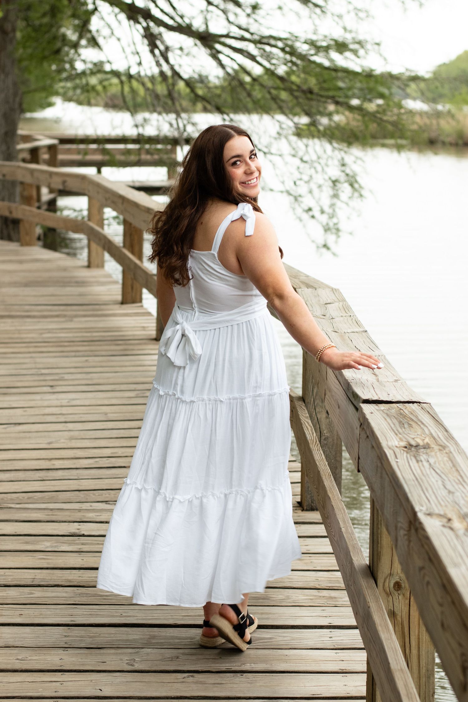 White tiered maxi dress portrait on wooden lakeside boardwalk.