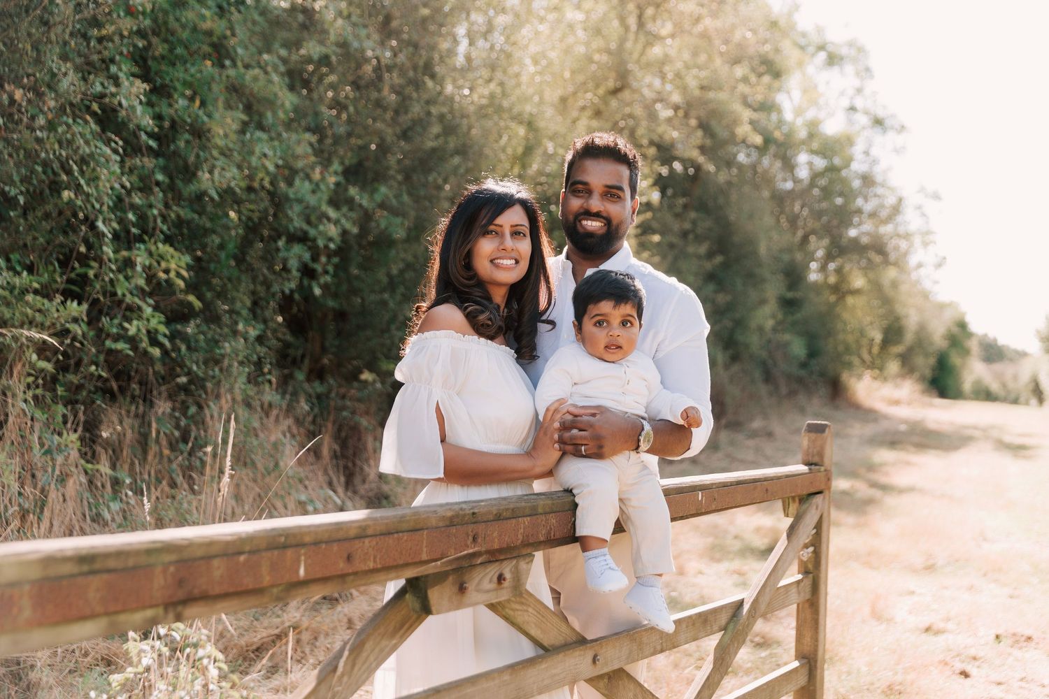 Family sitting together on rustic wooden logs in an outdoor autumn setting.