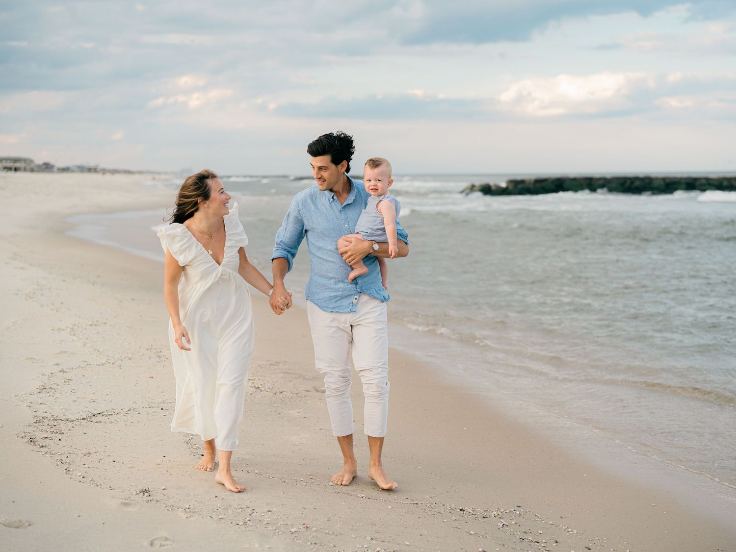 Spring Lake photographer capturing a family walking along the beach holding hands with their 2 year old.