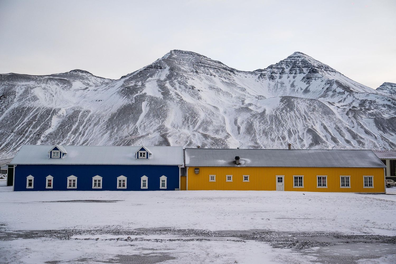 Panoramic view of snow-covered mountains and colorful buildings in a remote Arctic settlement during winter.