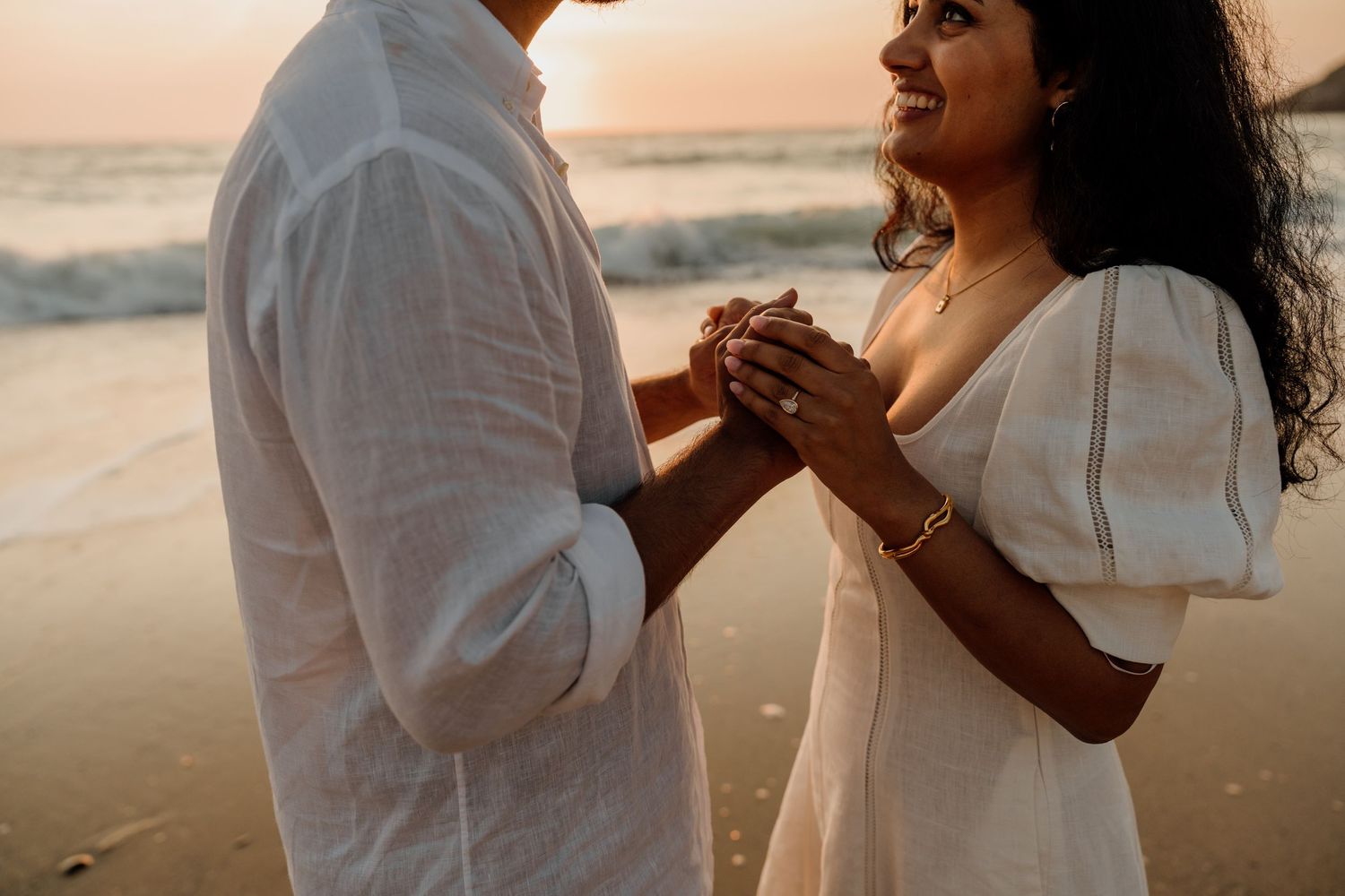 Couple sharing a romantic moment at holywell bay in cornwall after a surprise proposal