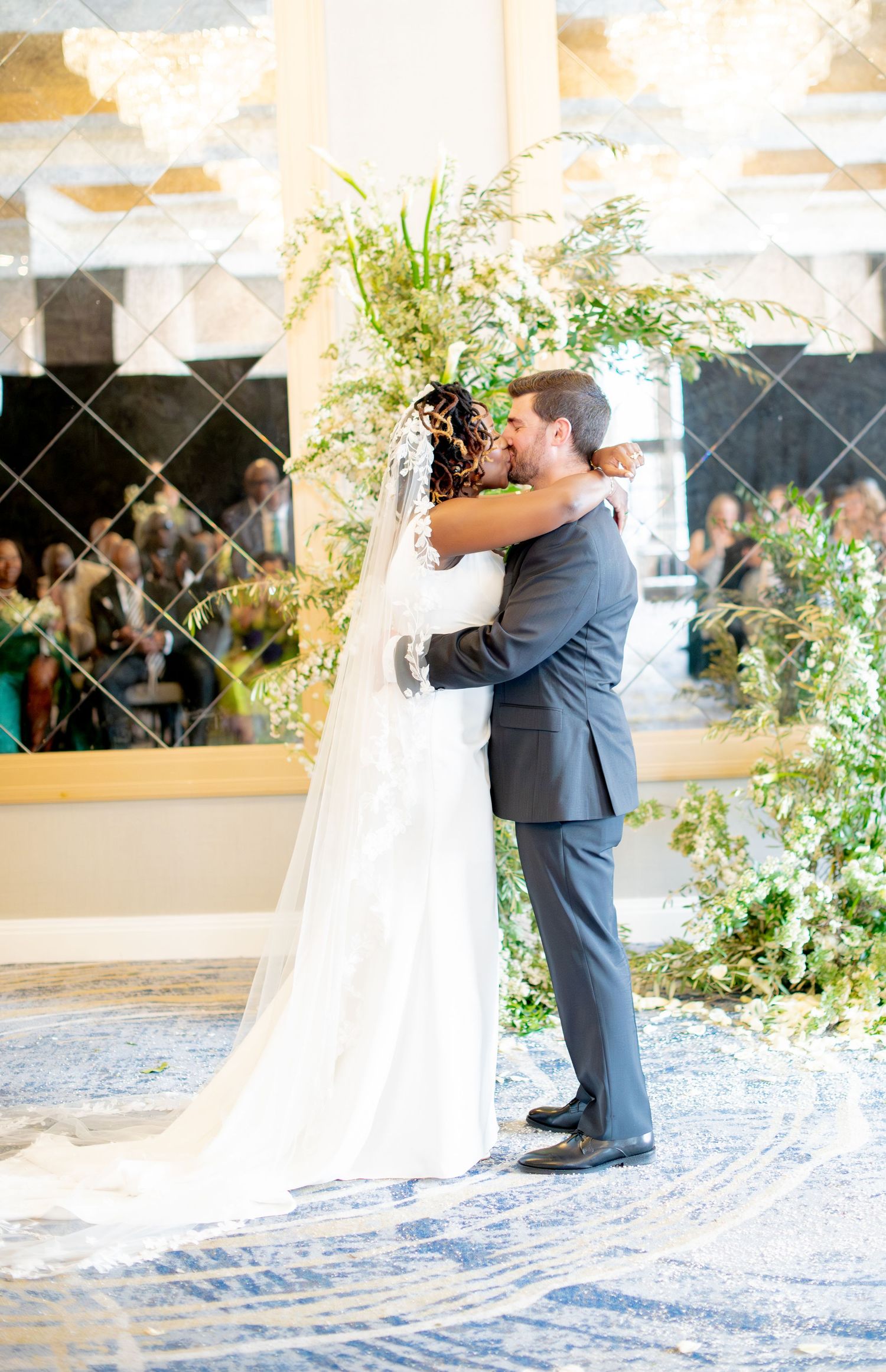 Bride and groom walk down the aisle after wedding ceremony, bride holds white floral bouquet.