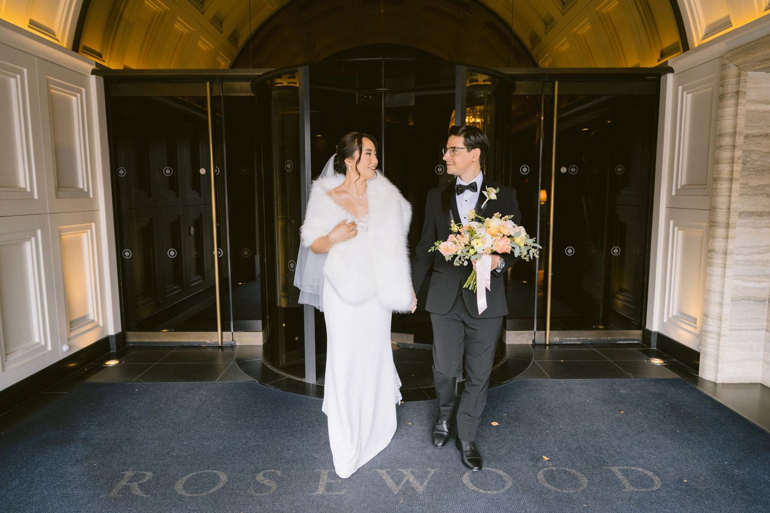 A bride and groom share a romantic moment together in a grand doorway of an elegant venue.