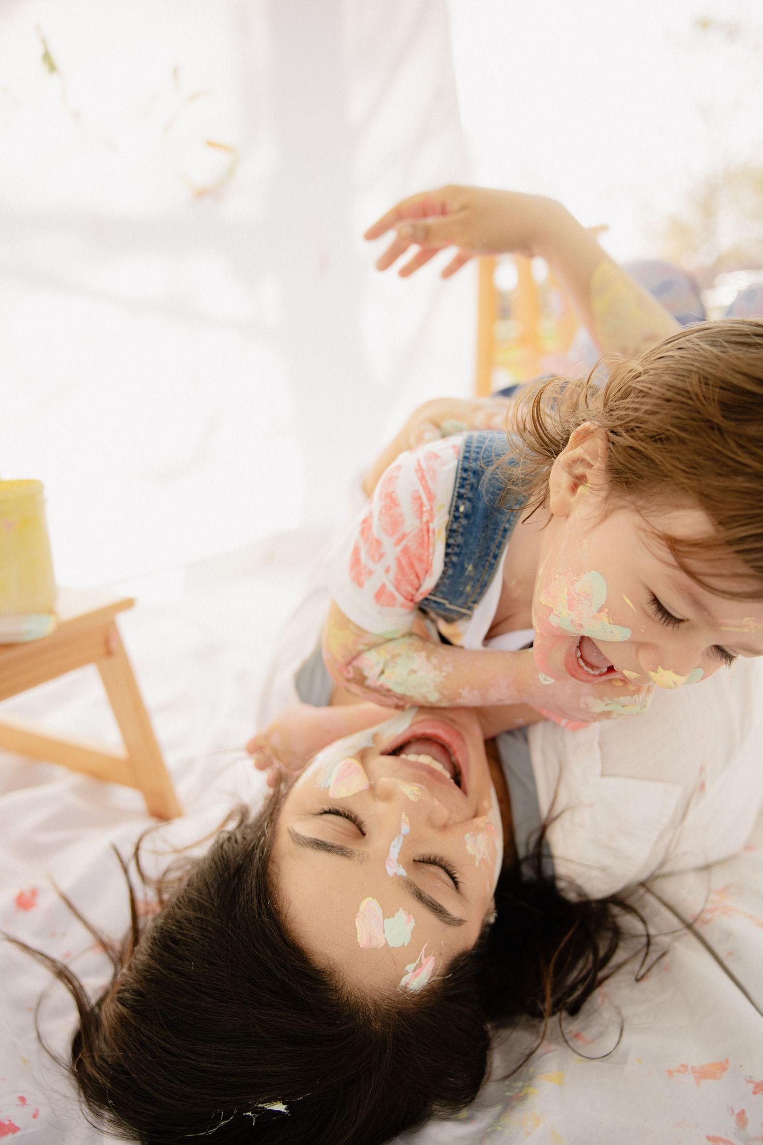 Two people lying down together sharing playful and joyful moments in a bright sunlit room. Mommy and Me Frederick Maryland