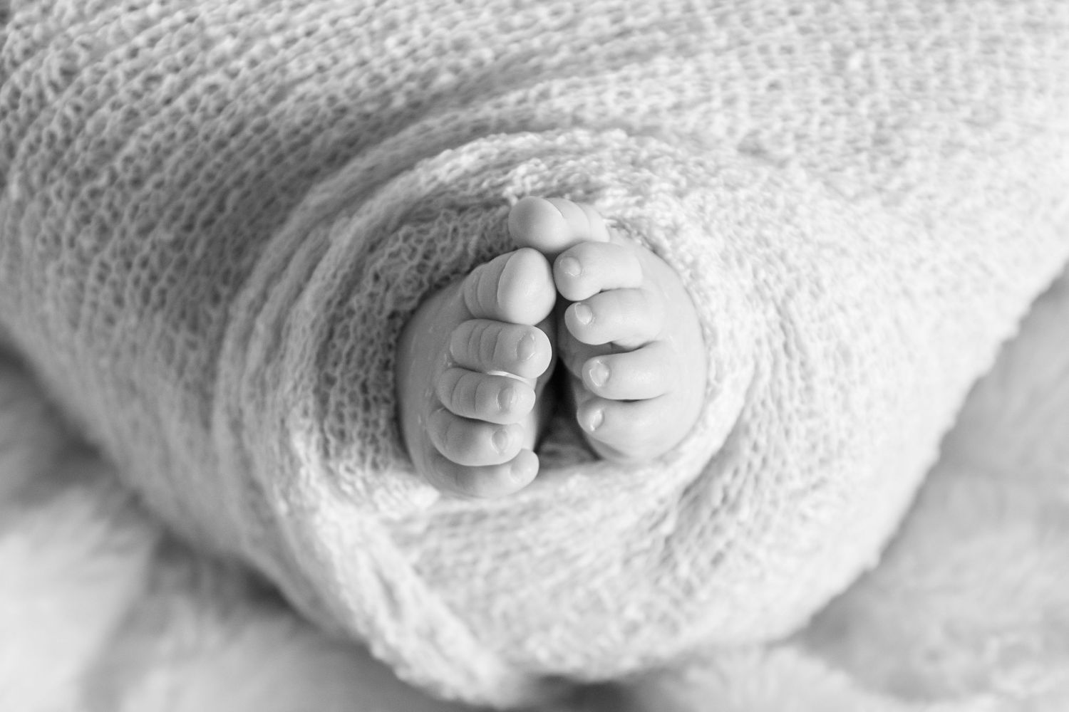 black and white image of a baby's feet wrapped in a wrap