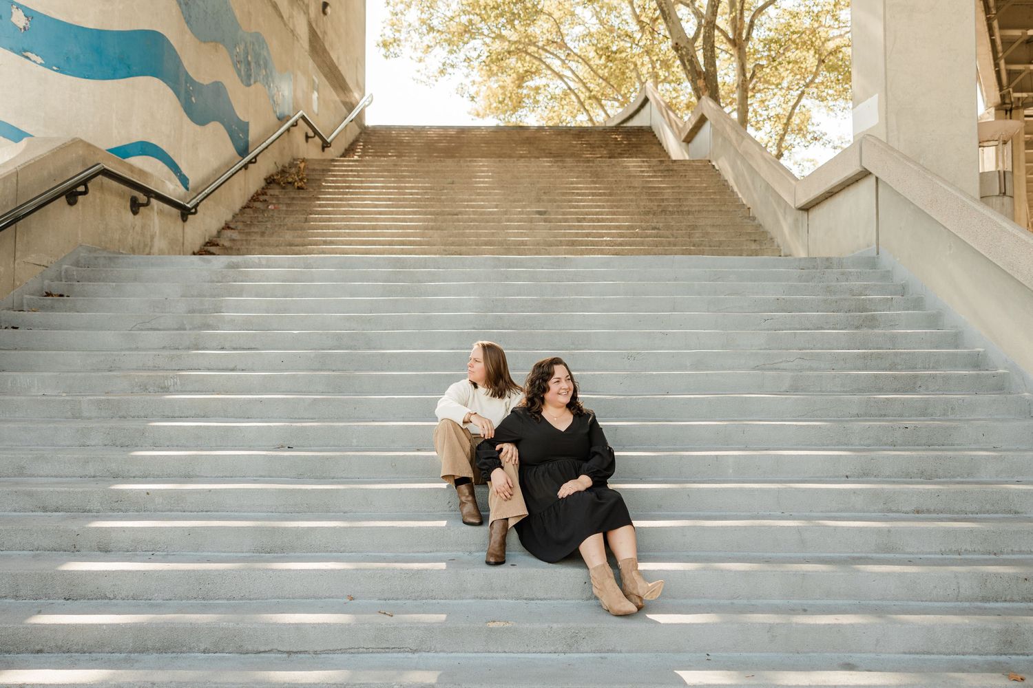 A couple poses for a series of romantic engagement photos on grand stone steps in warm sunlight.