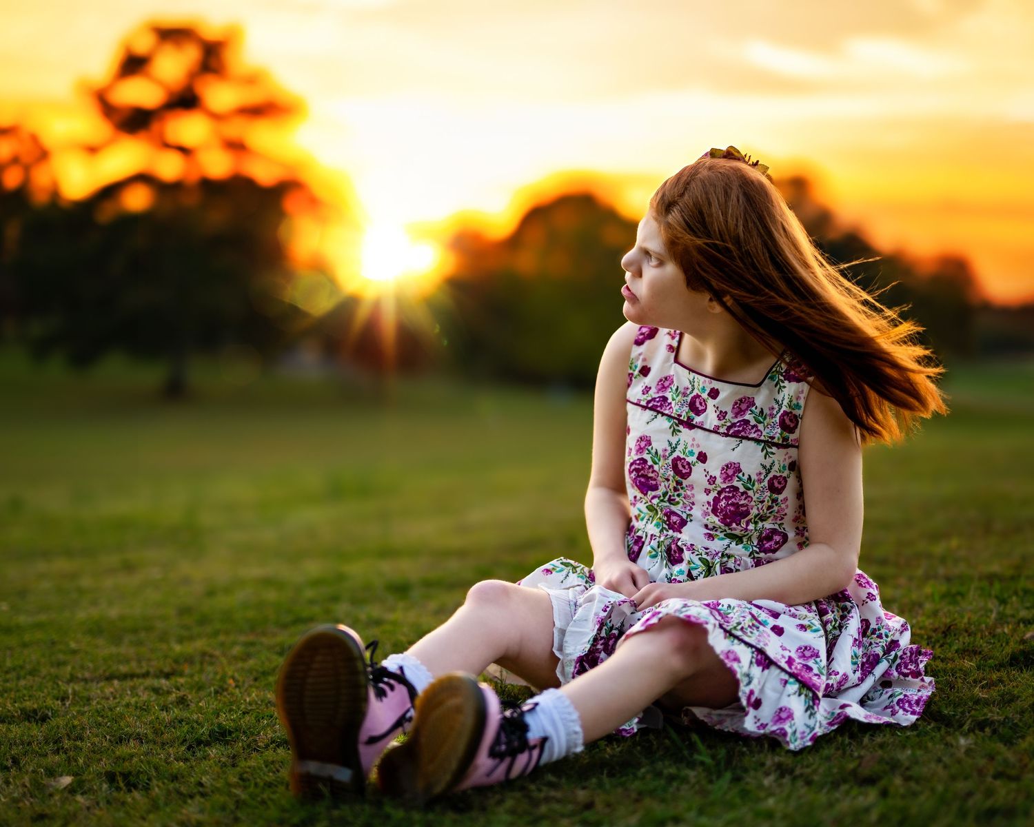 My daughter sitting in the sun looking off at the sunset.