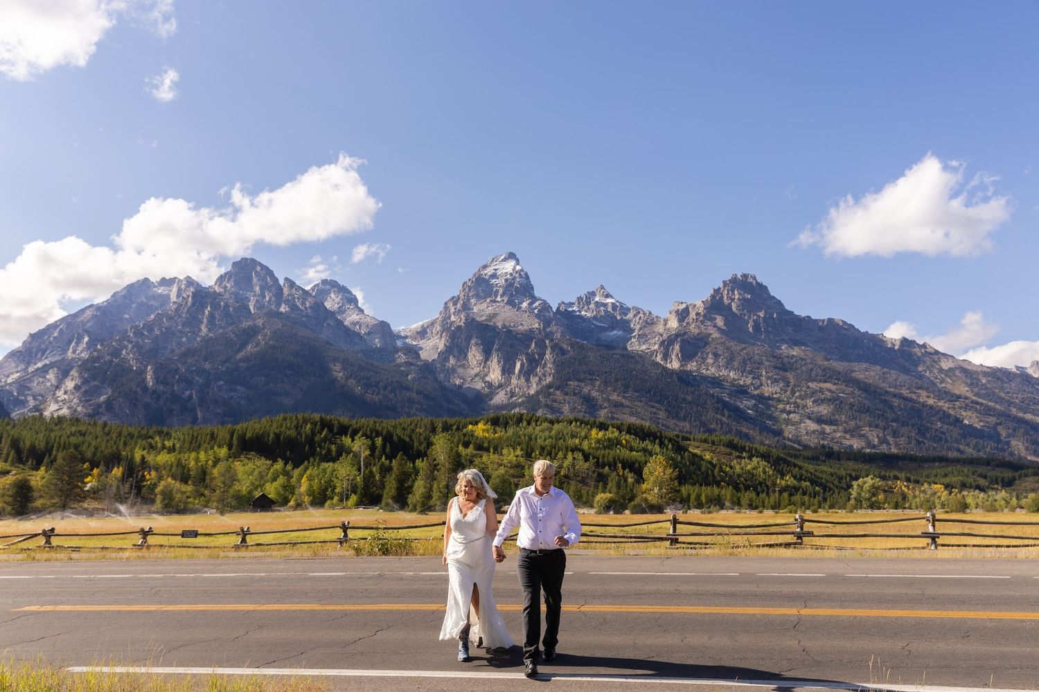 A couple in wedding attire shares an intimate moment on a snowy mountain peak with dramatic clouds in the background.
