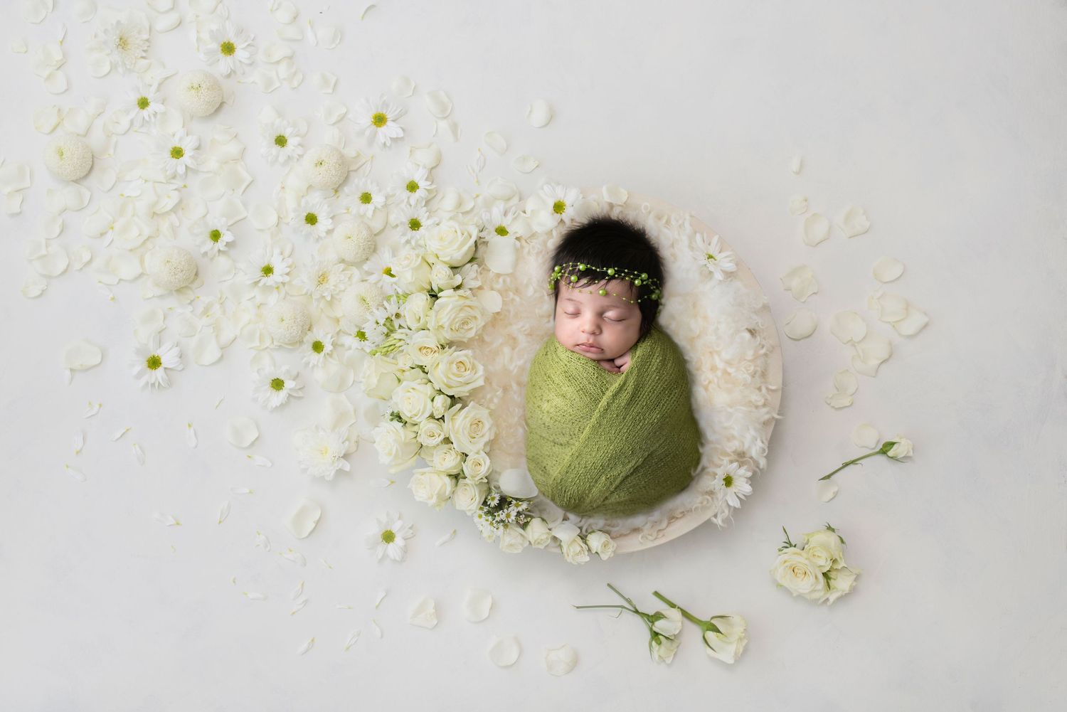 Collection of delicate and dreamy newborn portraits with white flowers and green wrapping in a soft vintage style.
