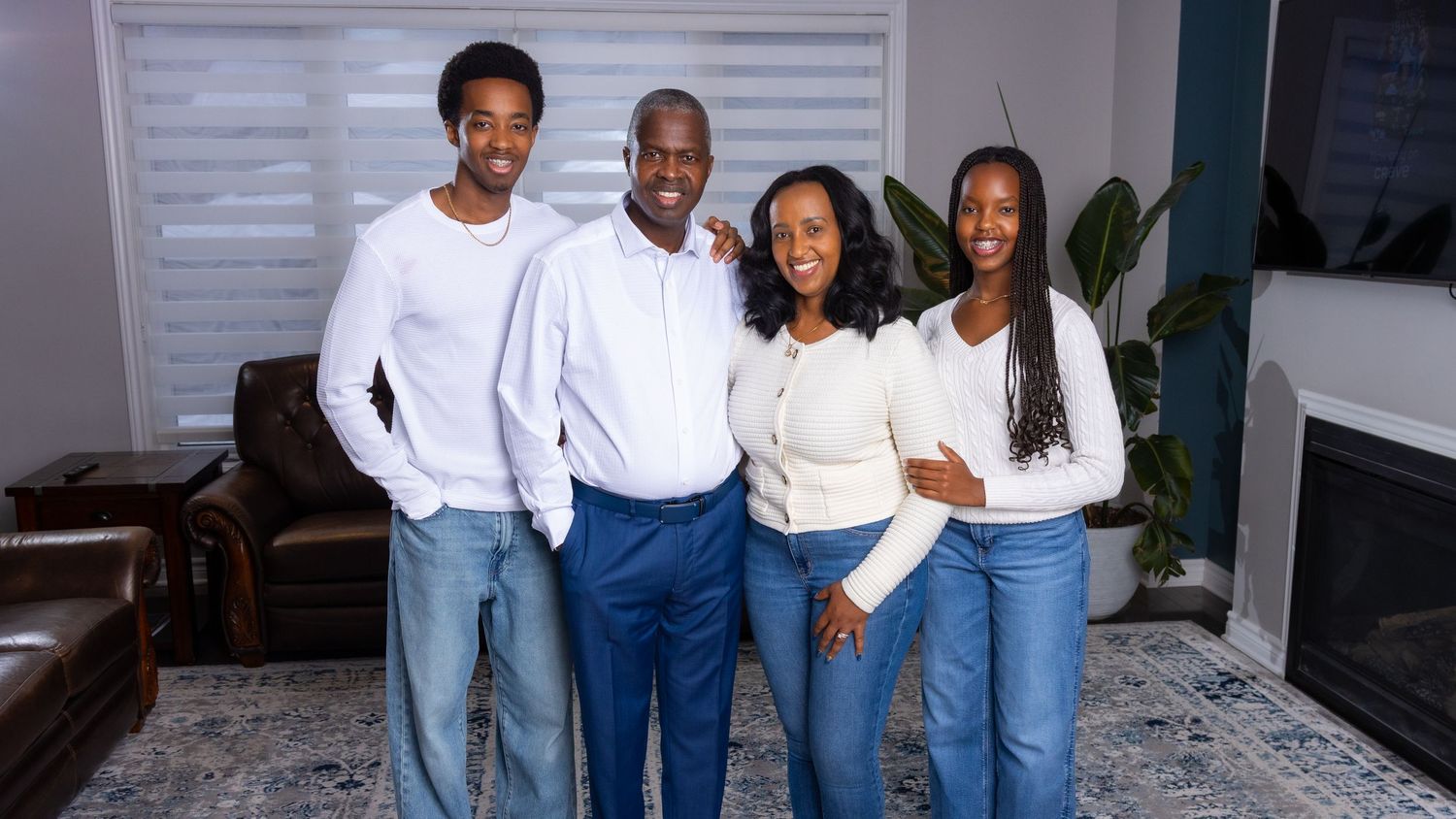 Family portrait in a Orléans home with parents, Pacifique and Alice, and two teenage children standing together in a well lit living room.