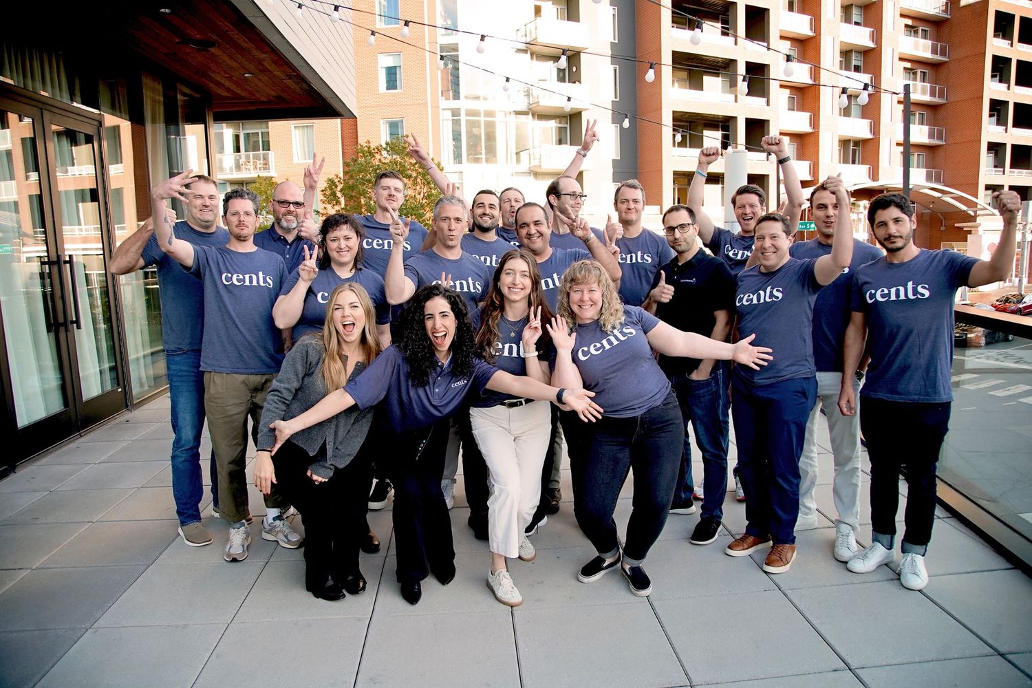 Large group of employees in matching blue uniforms gather for outdoor team photo.