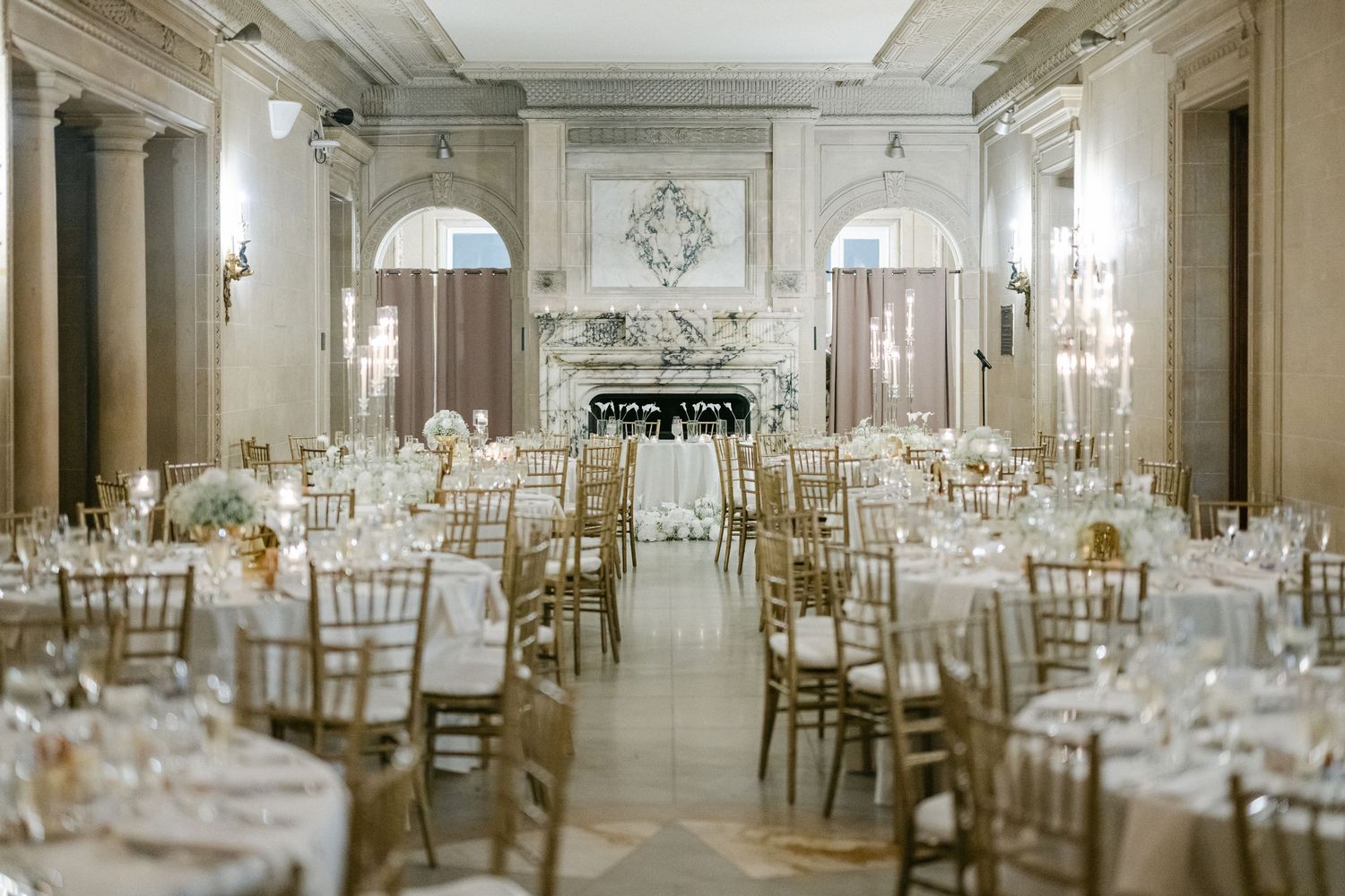 A bride in a flowing white wedding gown sits elegantly on a beige tiled bench in a modern interior setting. - The Armour House