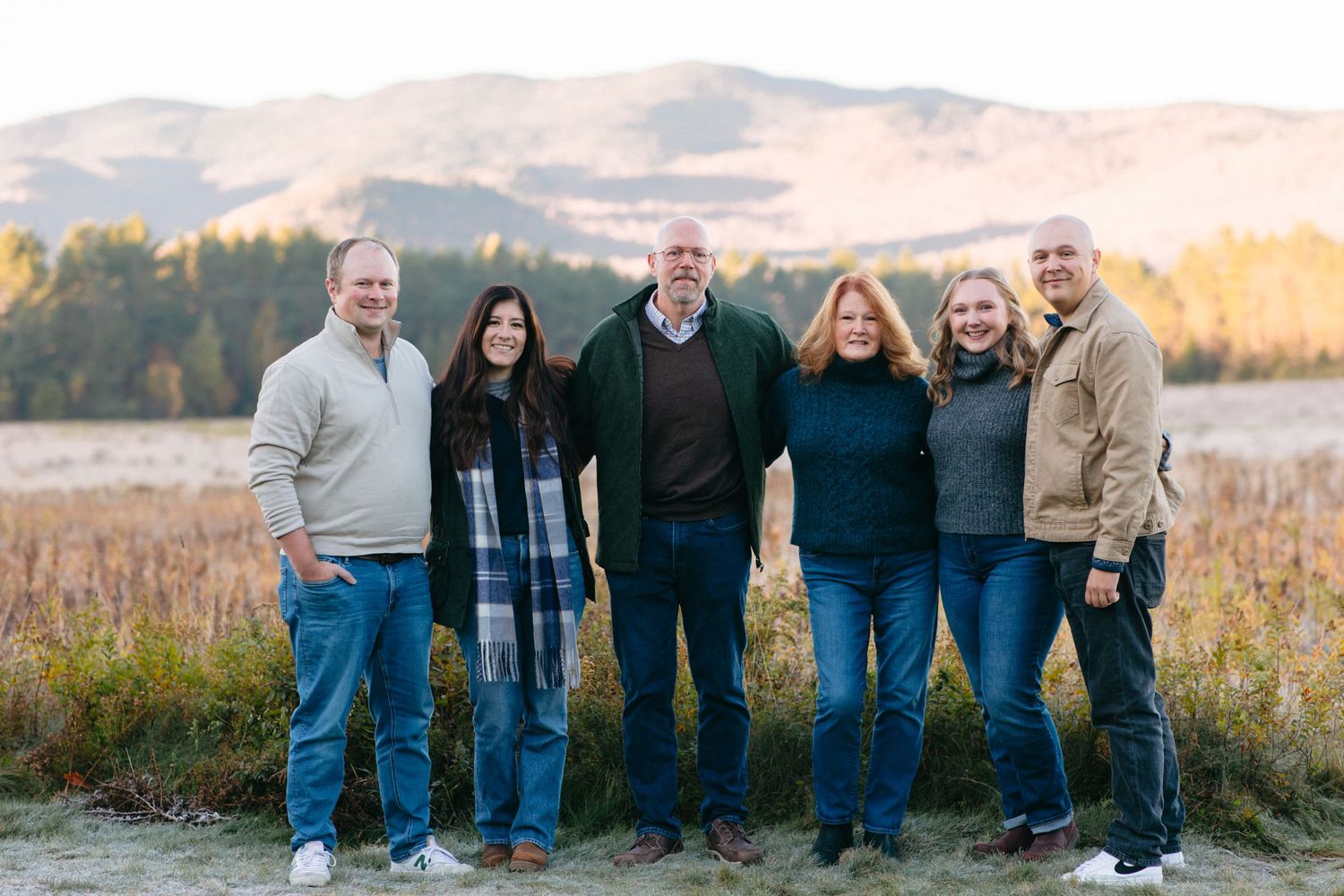 A group of people standing together outdoors in a field during golden hour sunset.