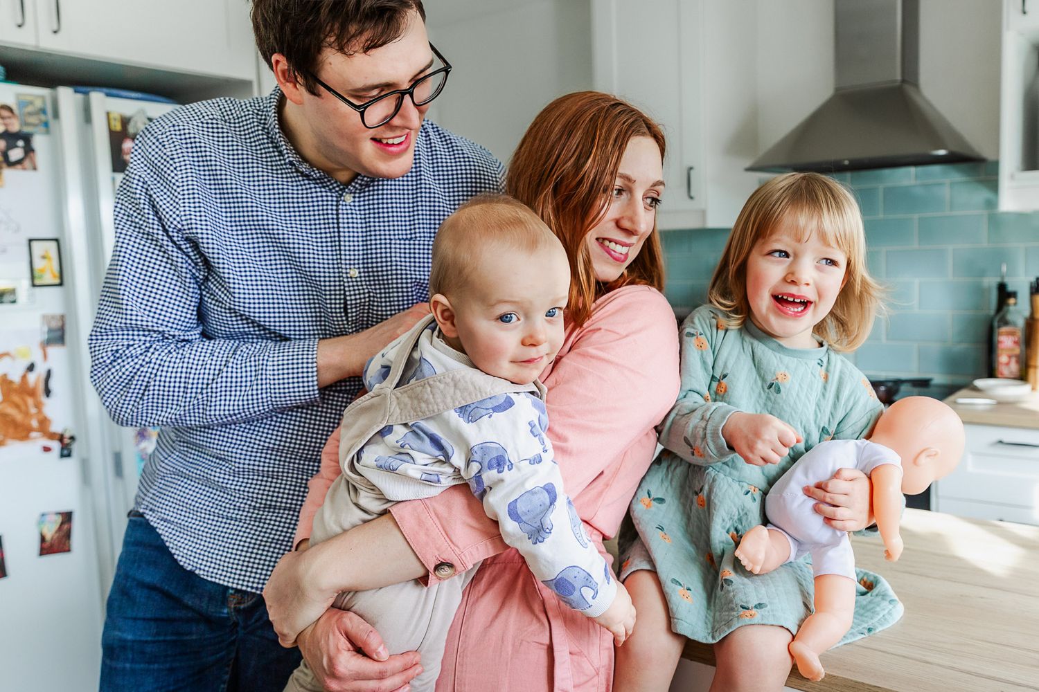 A family of four cuddle at the kitchen counter and smile. Bristol family photographer