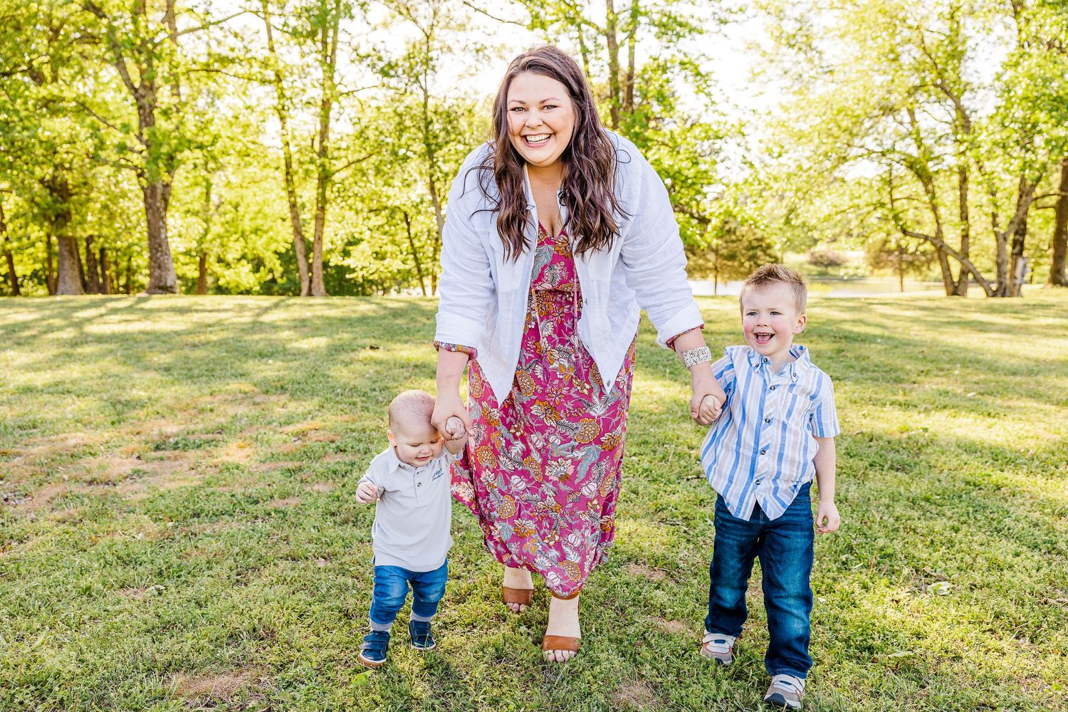 Family walking together in sunlit park during spring photoshoot.