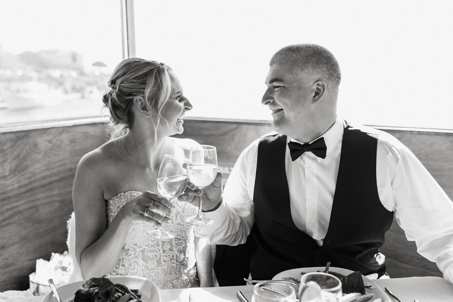 A romantic wedding couple shares an intimate moment while seated together at their reception table on a boat in San Diego.