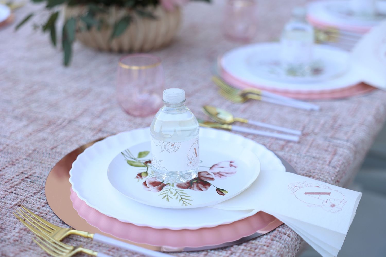 Bas Mitzvah decor setup. Charges, plates with a personalized water bottle set on a pretty prink tablecloth