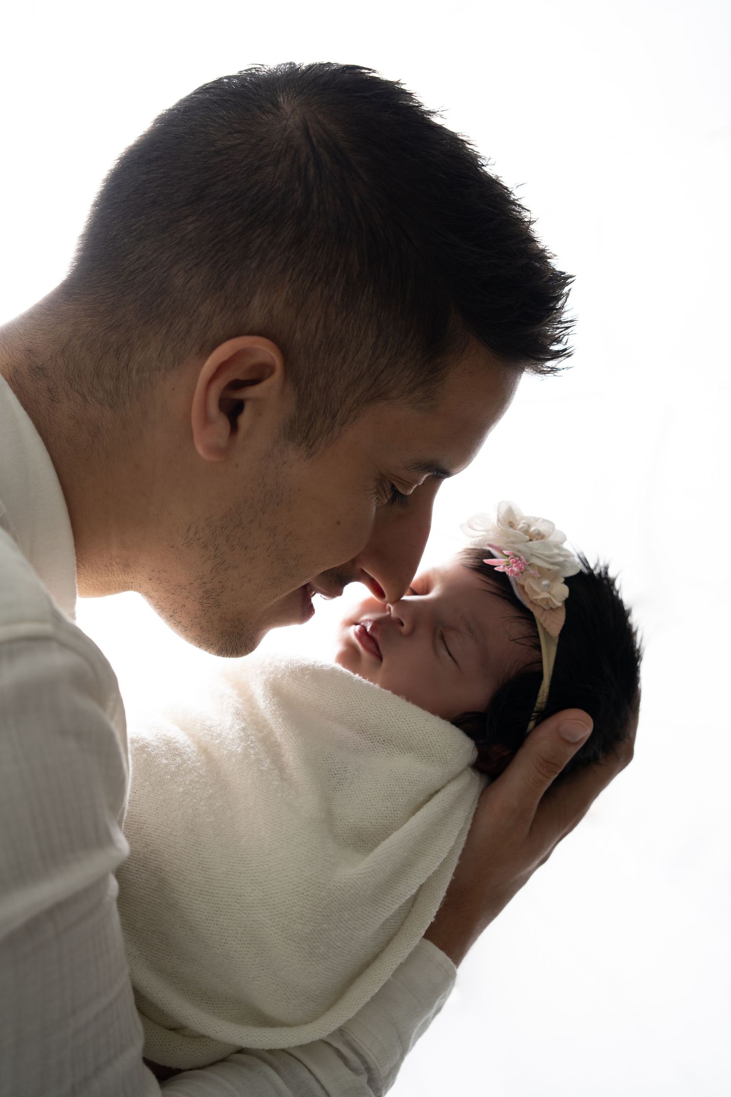 Father holding newborn baby during a new born photoshoot Dubai, captured by an expert new born photographer Dubai at Mohastudio.