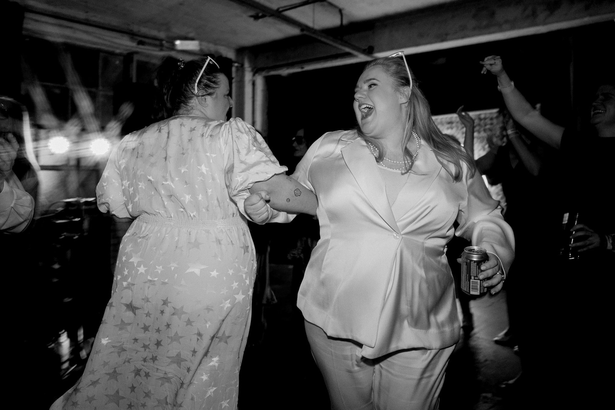 Two women dancing together at a party in black and white photography at a nightclub event.