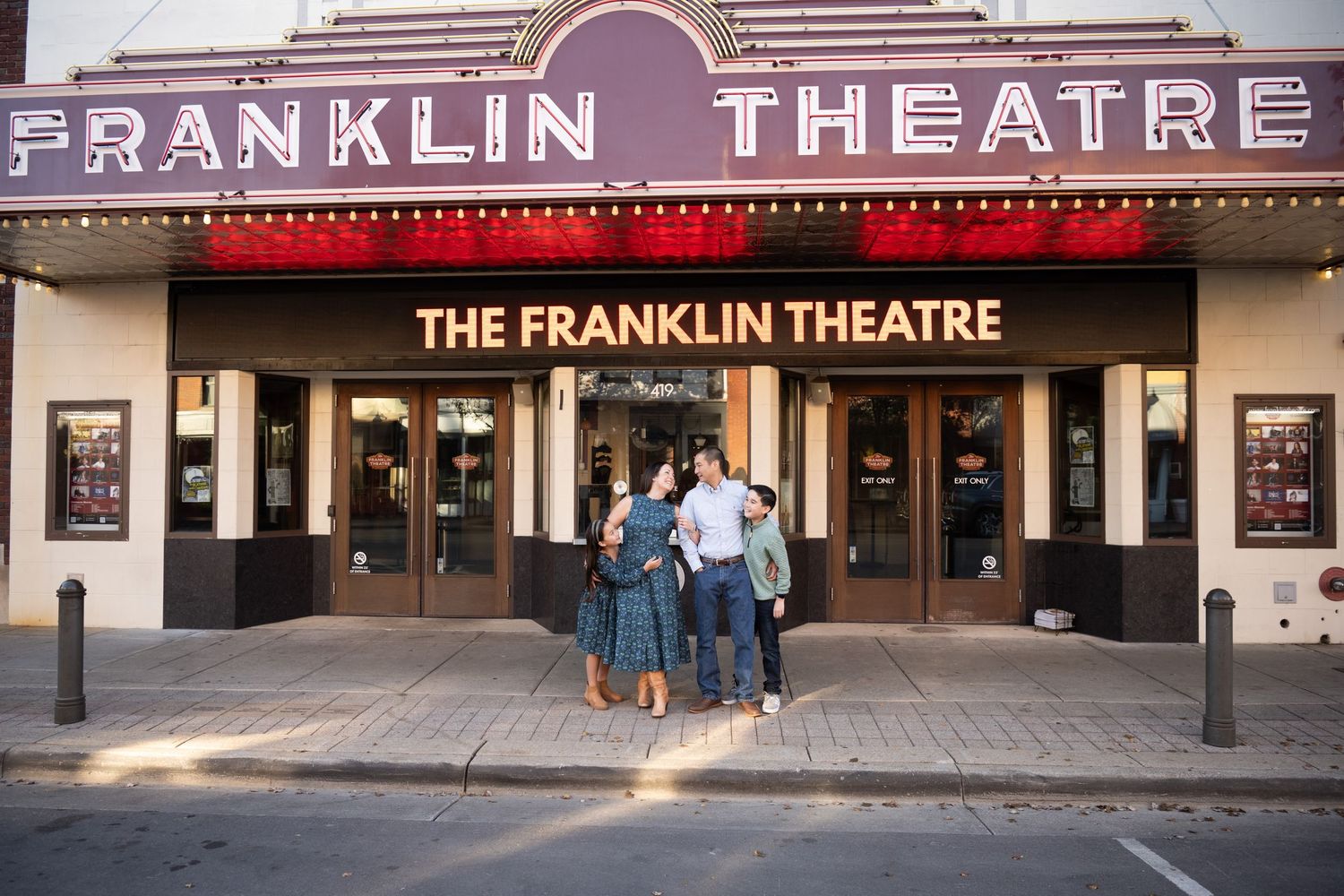 Group of friends hugging outside the Franklin Theatre marquee at dusk in Franklin, Tennessee.