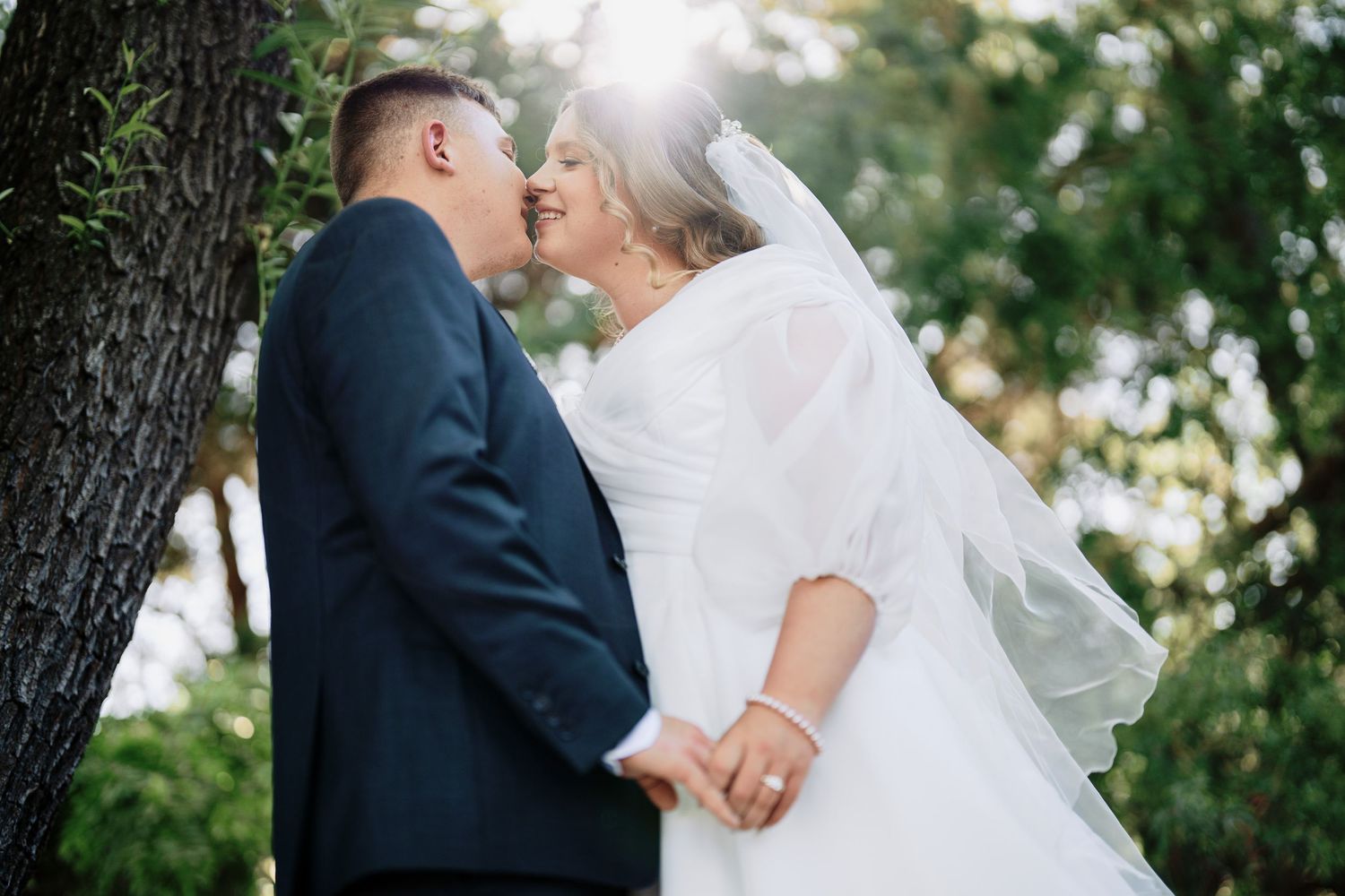 Groom kisses bride in a sunlit garden, wedding photography by Purple Bird Photo, Sydney & Wollongong