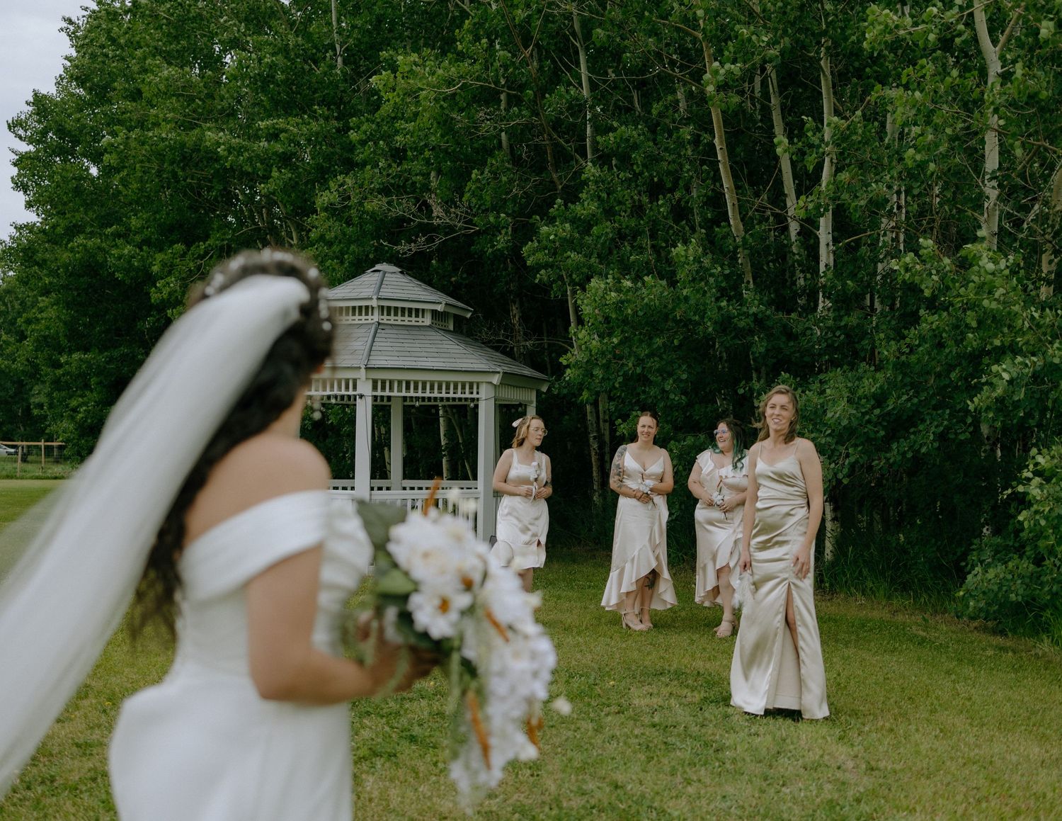 A wedding scene in a garden with a gazebo backdrop and bridesmaids in elegant dresses.