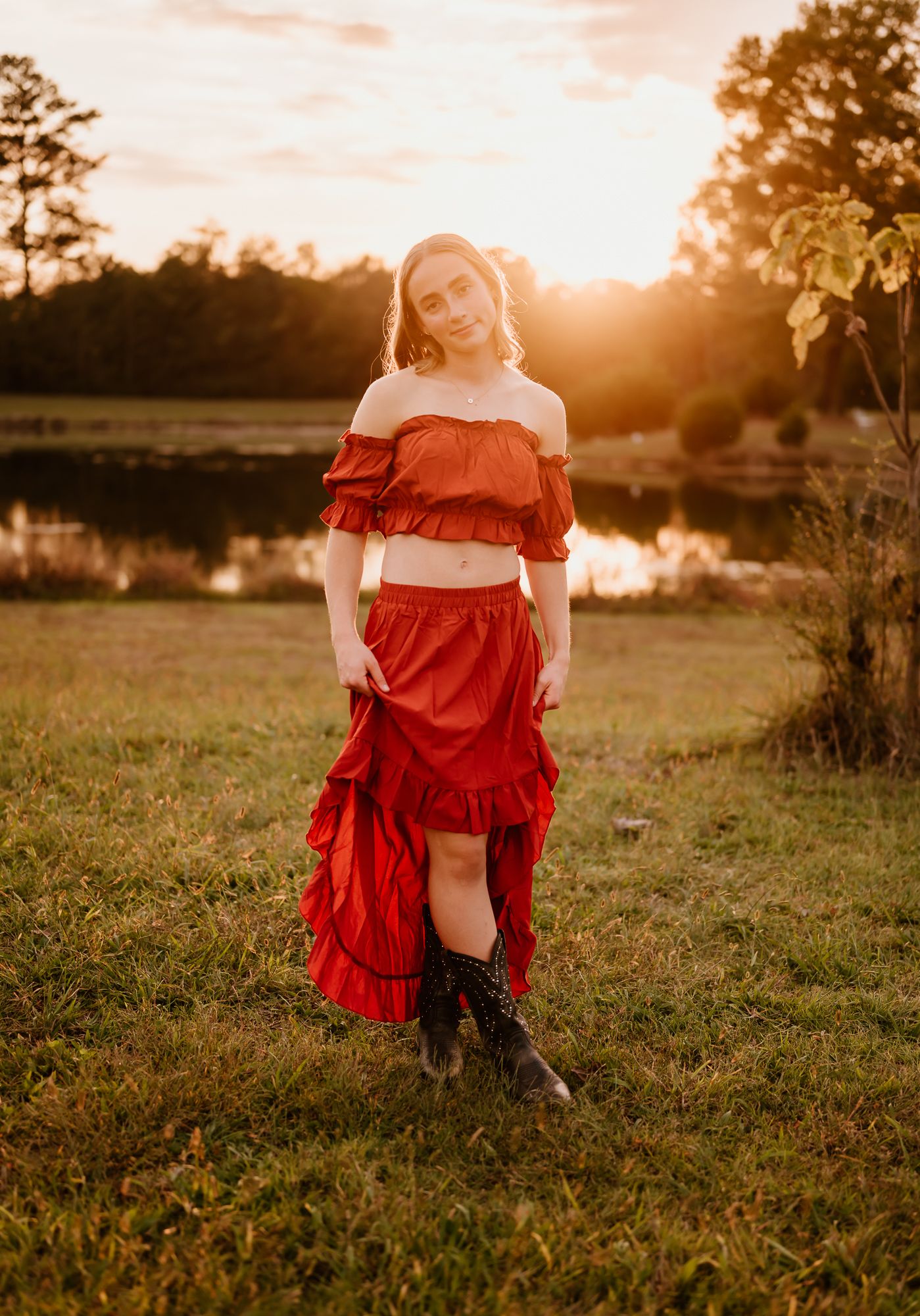Person in flowing blue dress stands in golden field during sunset.