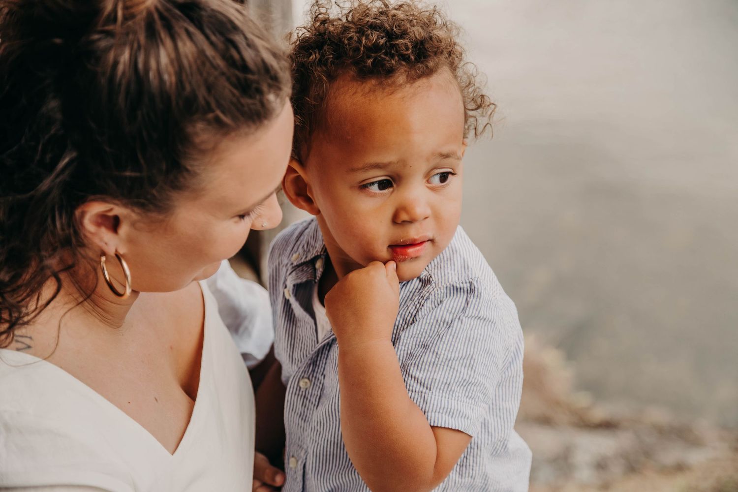 Tender moment between adult and toddler against grey background.