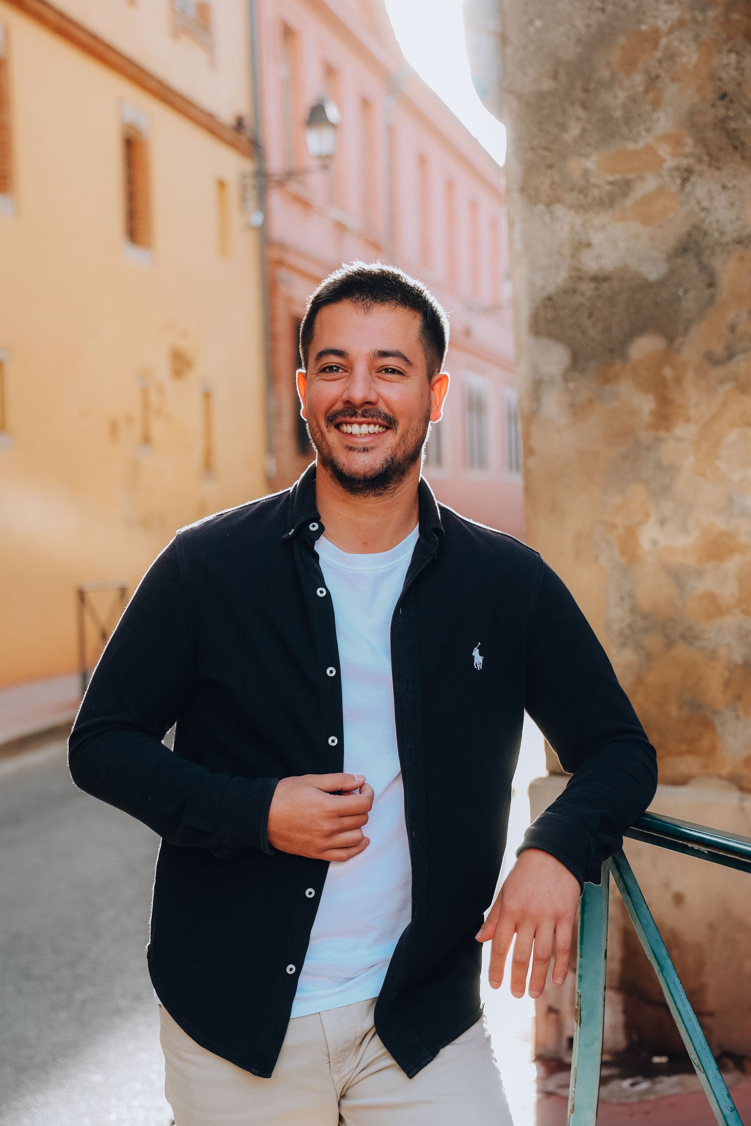 Casual portrait in front of peach-colored walls in Mediterranean setting.