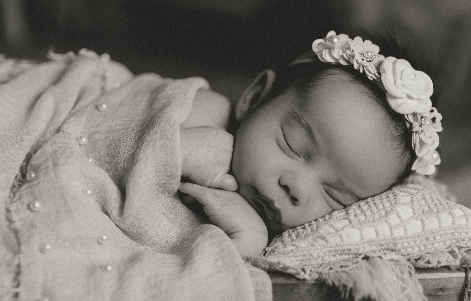 Sleeping newborn wearing floral headband rests on lace pillow in black and white photo.Colorado Springs Photographer