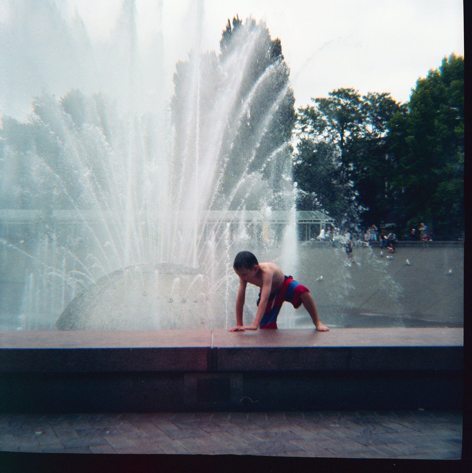 Seattle family photographer: A young boy plays at the International Fountain at the Seattle Center during the summer time
