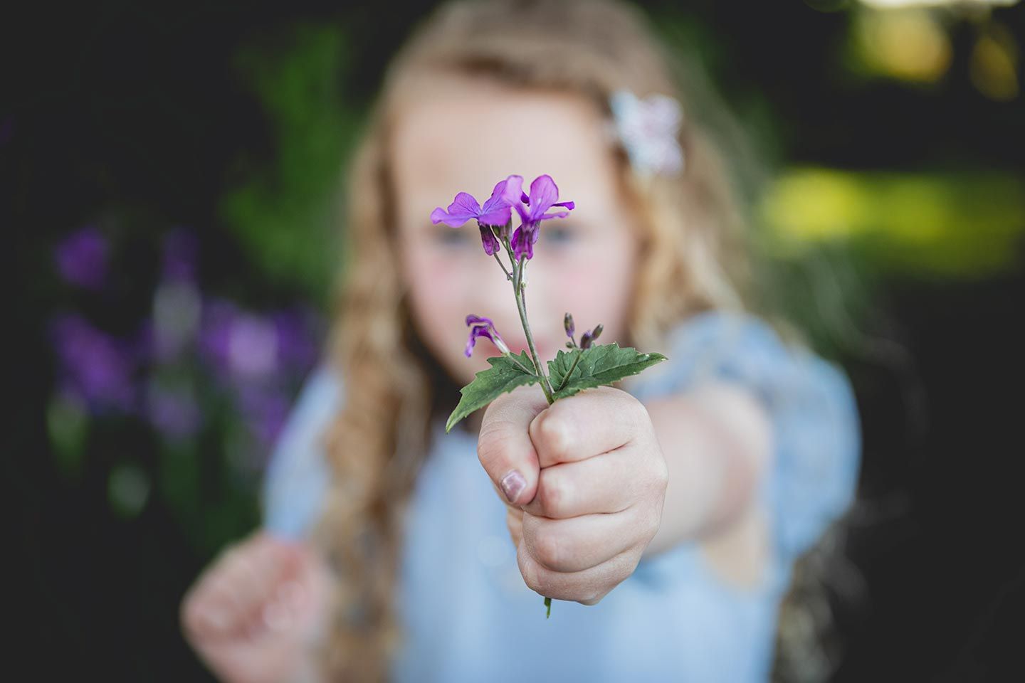 girl holding a flower the is in focus while she is out of focus
