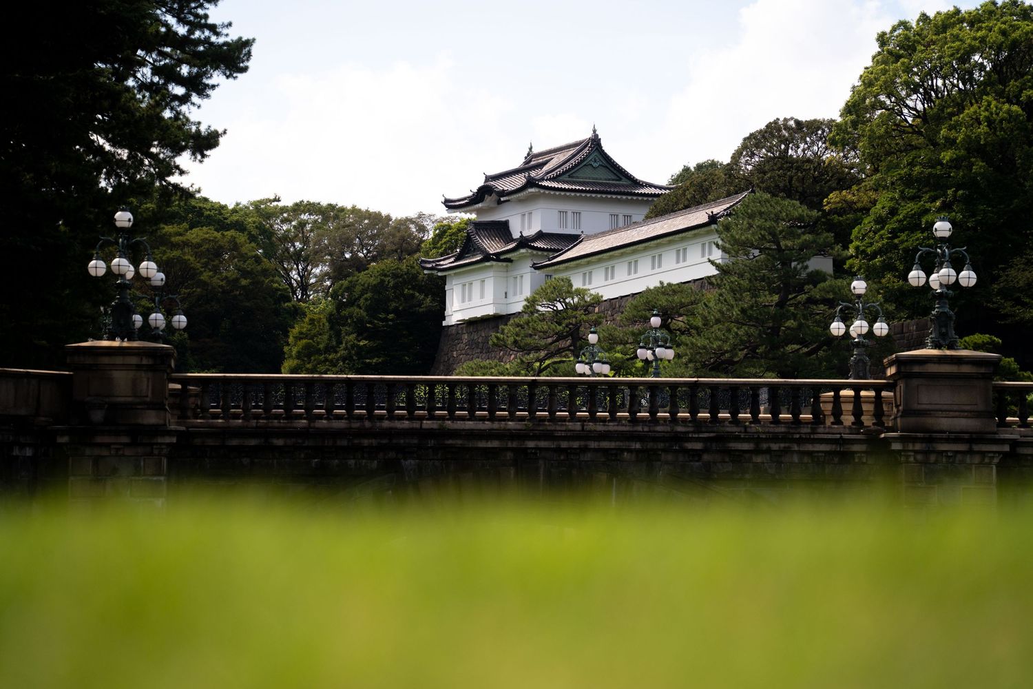 Traditional Japanese castle building with curved roofs set among green trees.
