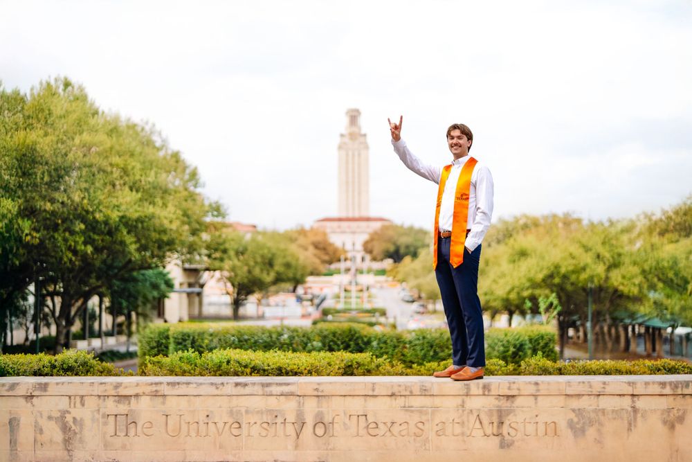 Joyful students play around a fountain at the University of Texas campus with the iconic UT Tower visible in the background.