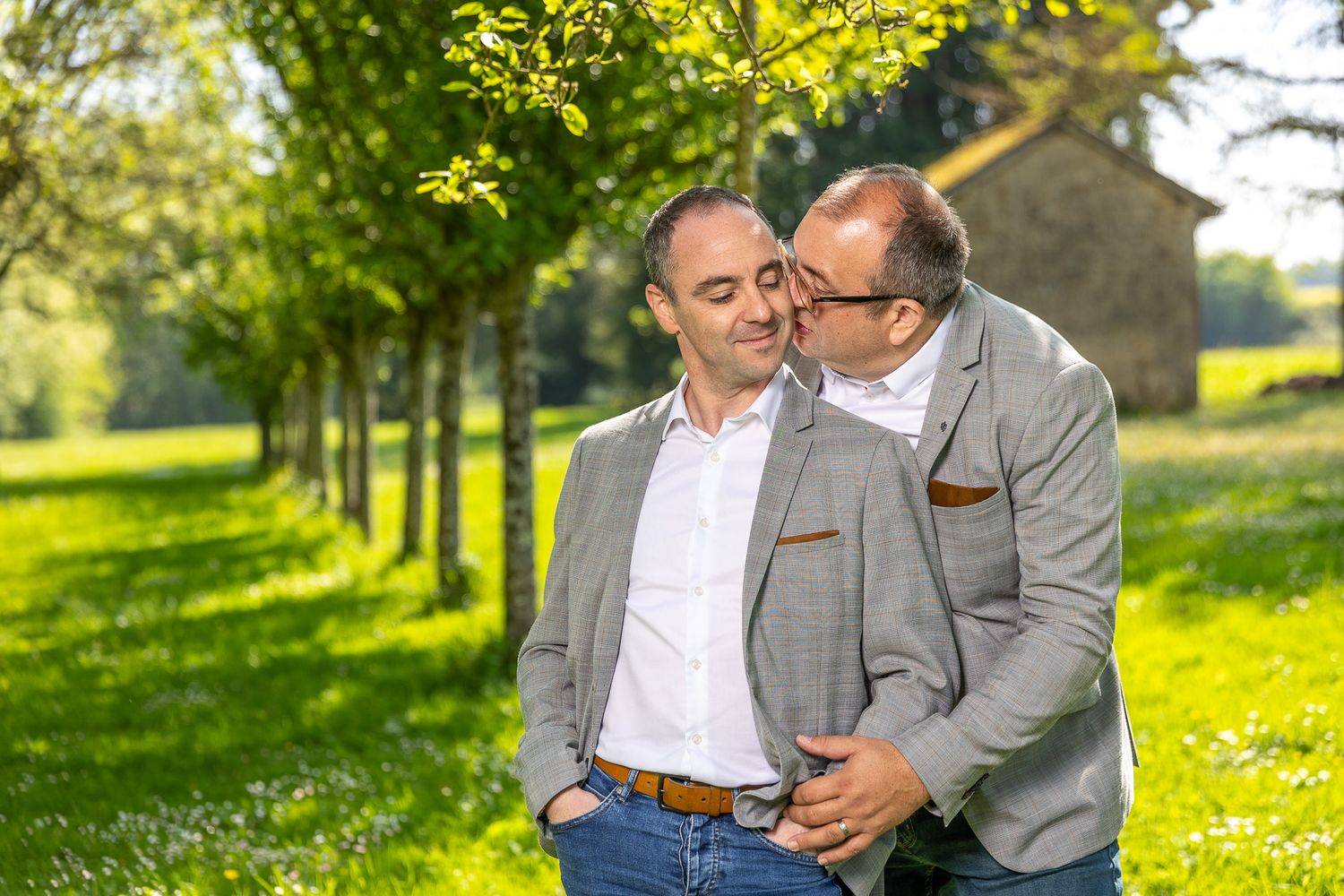 Romantic couple photoshoot in sunny meadow with yellow wildflowers.