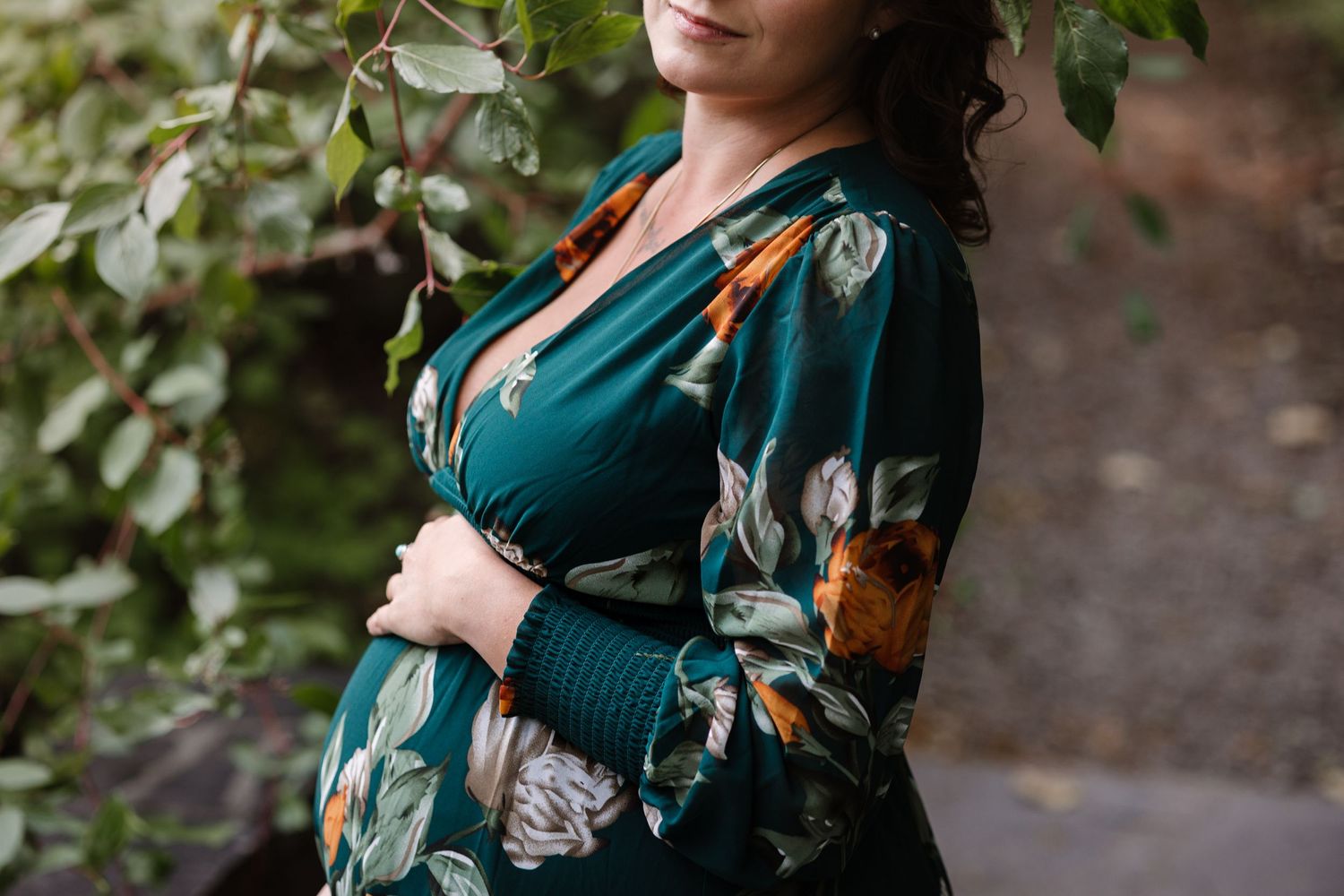Close-up of a teal floral dress with orange accents against natural foliage.