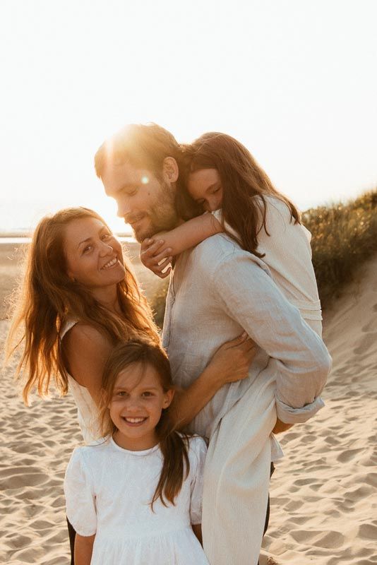 A family shares joyful moments together on a sandy beach during golden hour sunset.